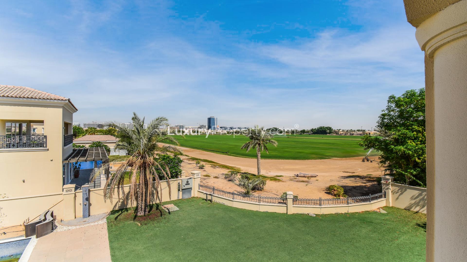 Luxurious Arabian Ranches villa with spacious driveway, palm trees, and elegant façade for sale