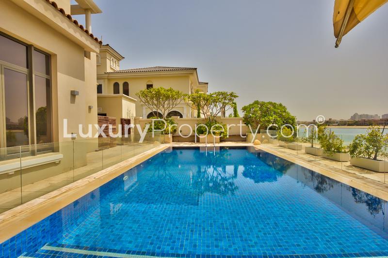 Modern kitchen in 6-bedroom Palm Jumeirah villa, featuring sleek cabinets and wooden island