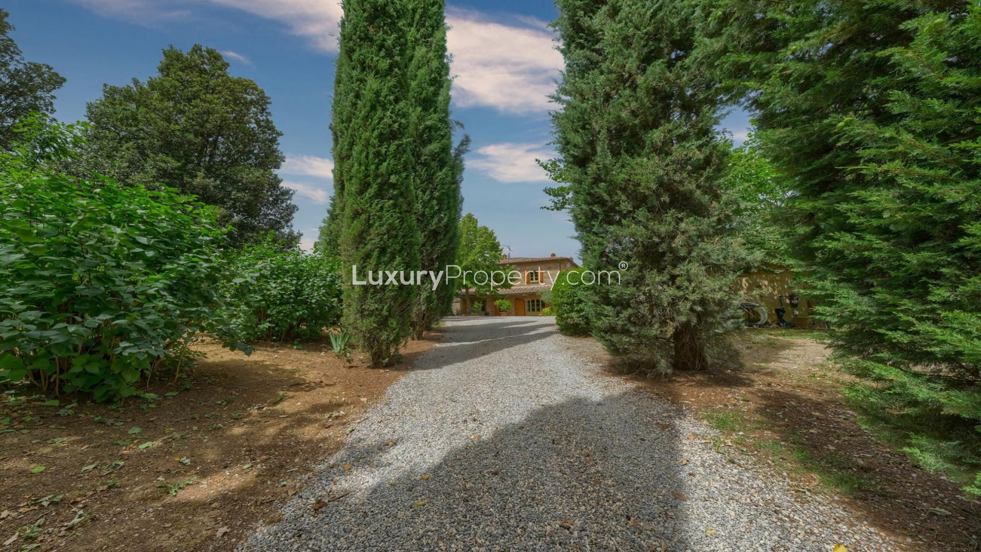 Charming stone villa exterior in Arezzo, surrounded by lush greenery and gravel driveway