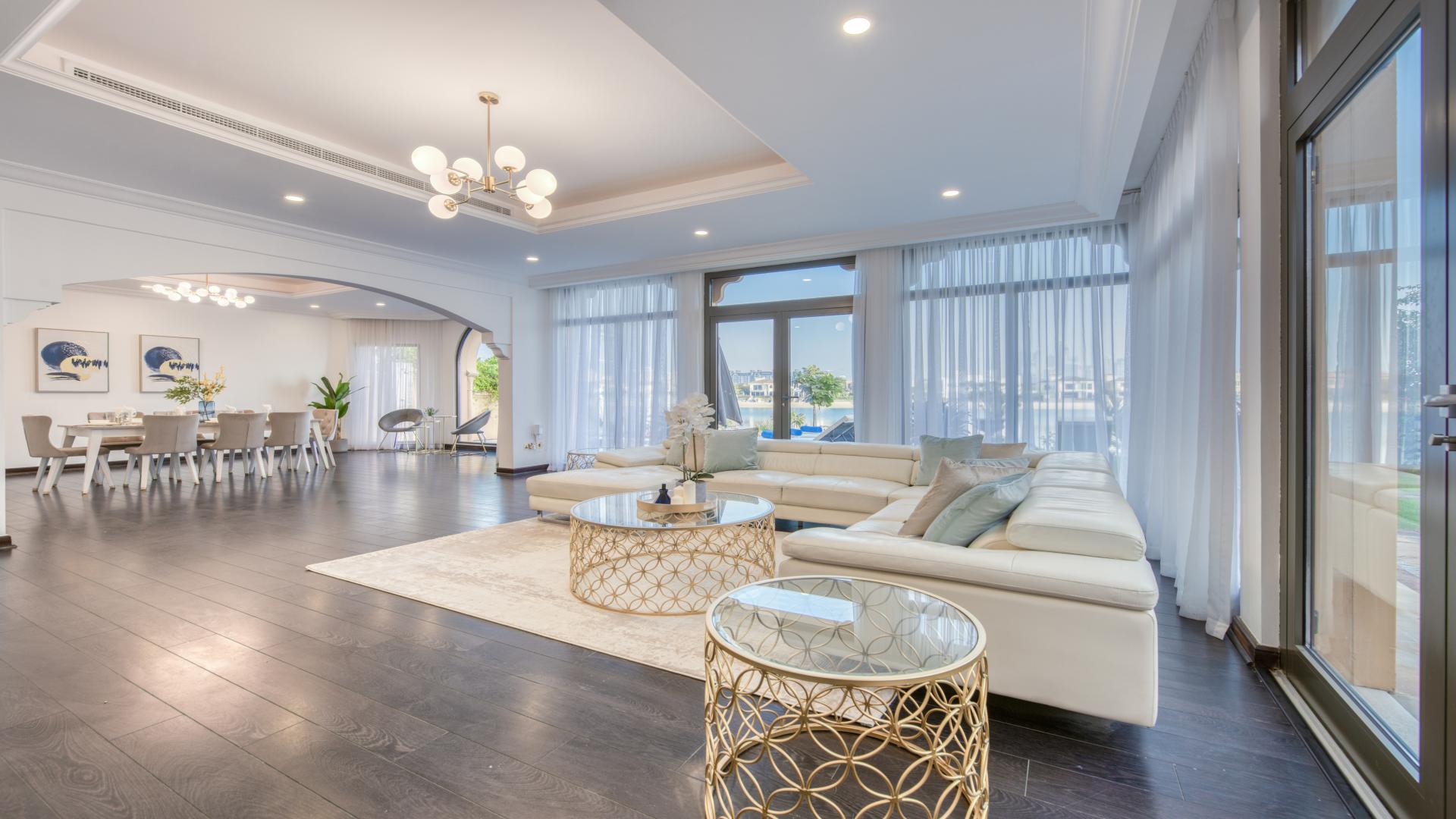 "Modern Palm Jumeirah villa exterior with garage, palm trees, and driveway in Garden Homes.",Modern living room in Palm Jumeirah villa with elegant decor and large windows