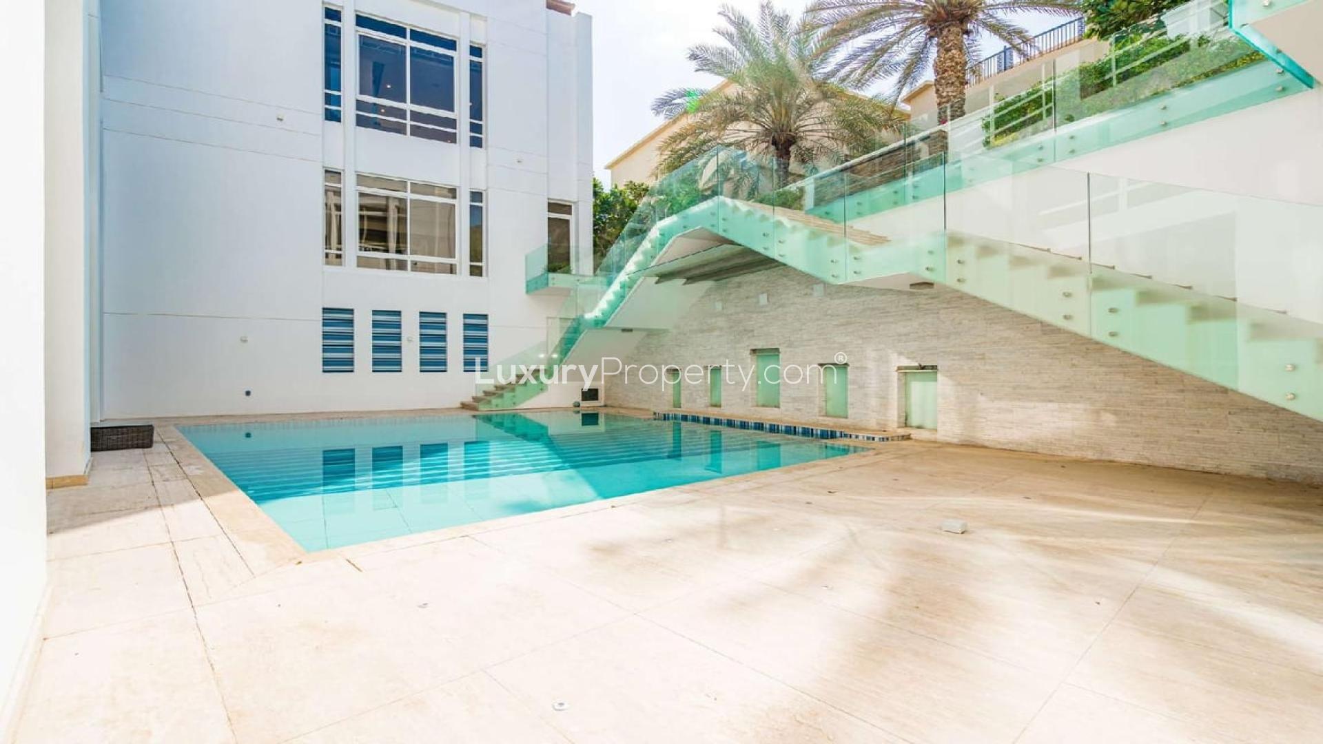 Outdoor pool area of luxury villa in Emirates Hills, Dubai, with modern glass staircase