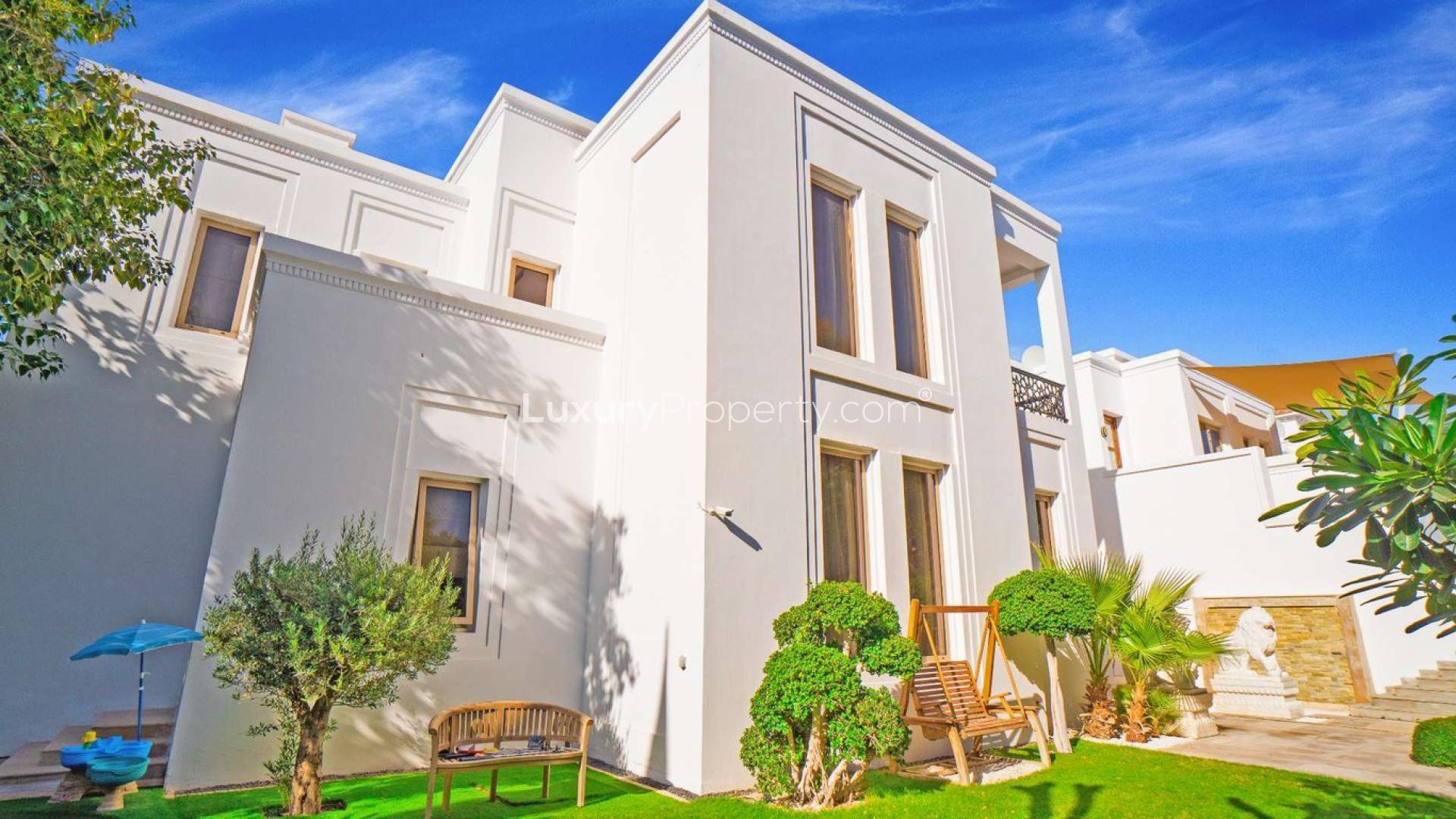 Luxurious Al Barari villa exterior with garage and luxury cars, lush greenery surrounds