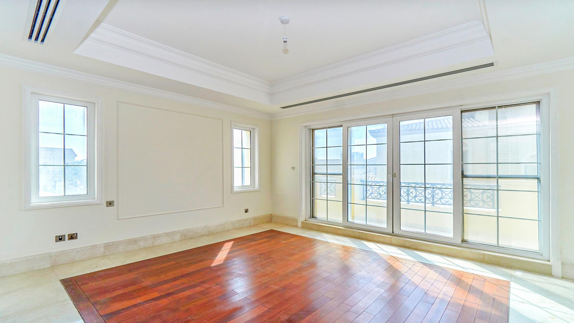 Spacious villa room with elegant wood flooring and arched windows in Arabian Ranches