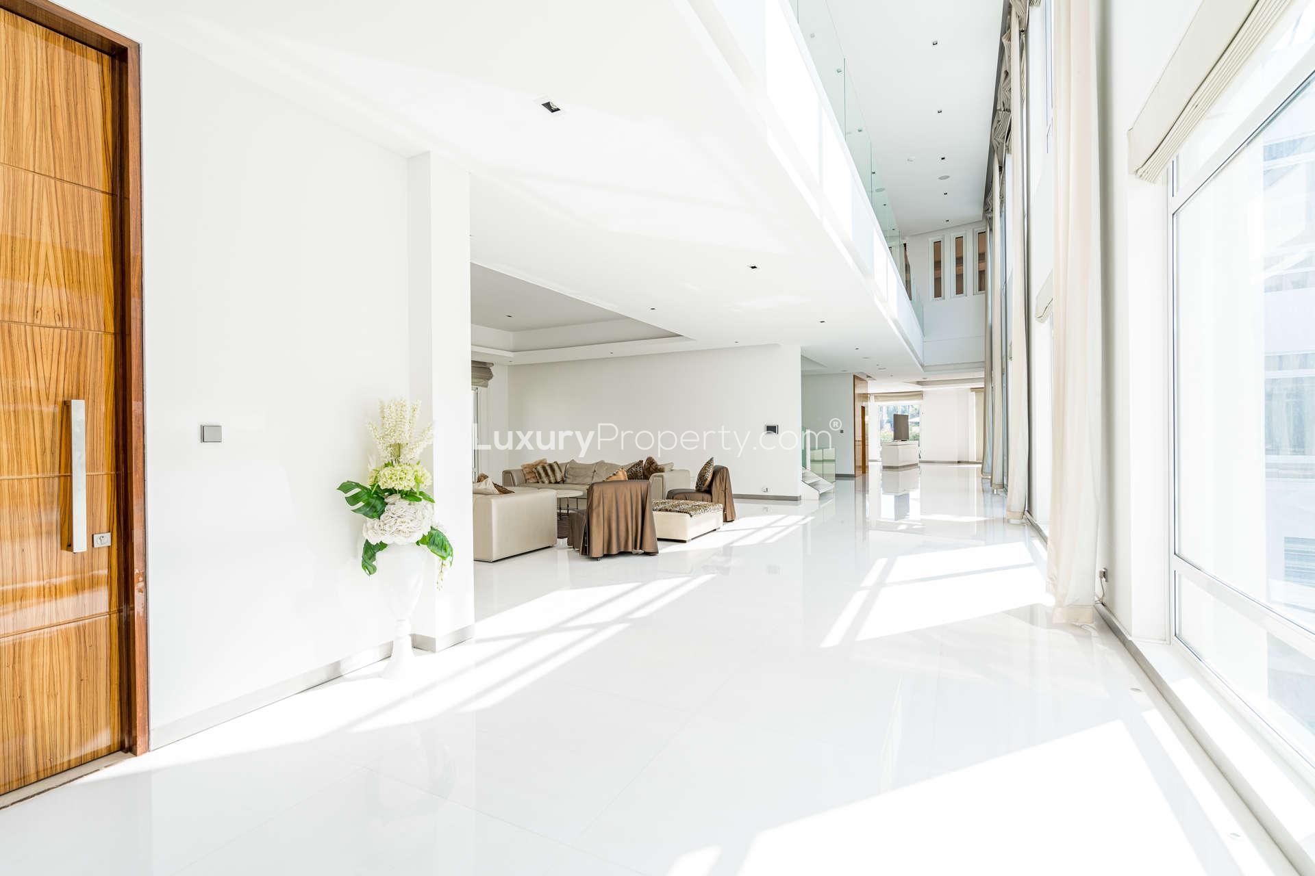 Alt text: "Scenic view of lush greenery and skyline from Emirates Hills villa, Dubai.",Luxurious open-plan living area in 7-bedroom villa, Emirates Hills, Dubai