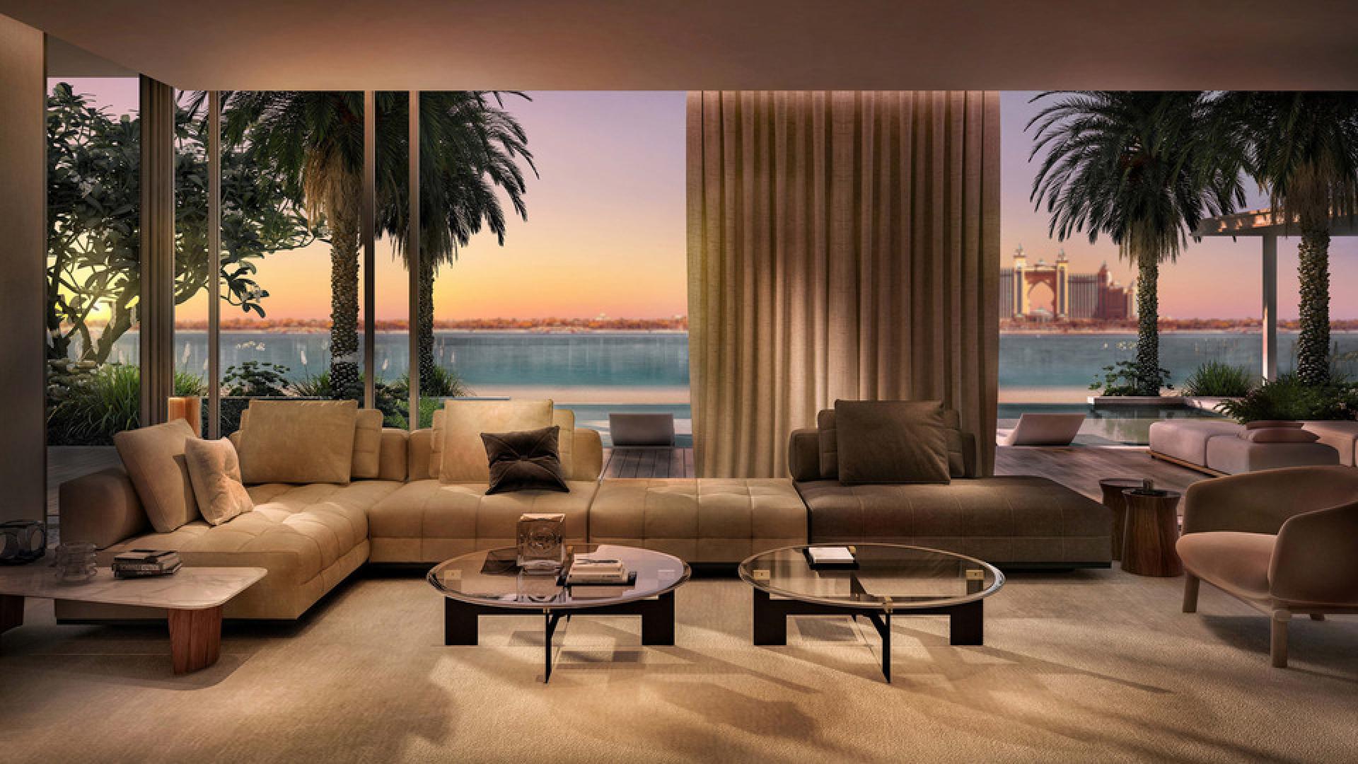 Beachfront villa terrace with dining table, pool, and ocean view at sunset, Palm Jumeirah