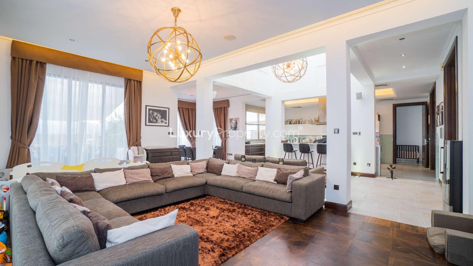 Elegant Al Barari villa exterior with lush garden and seating area, listed for sale