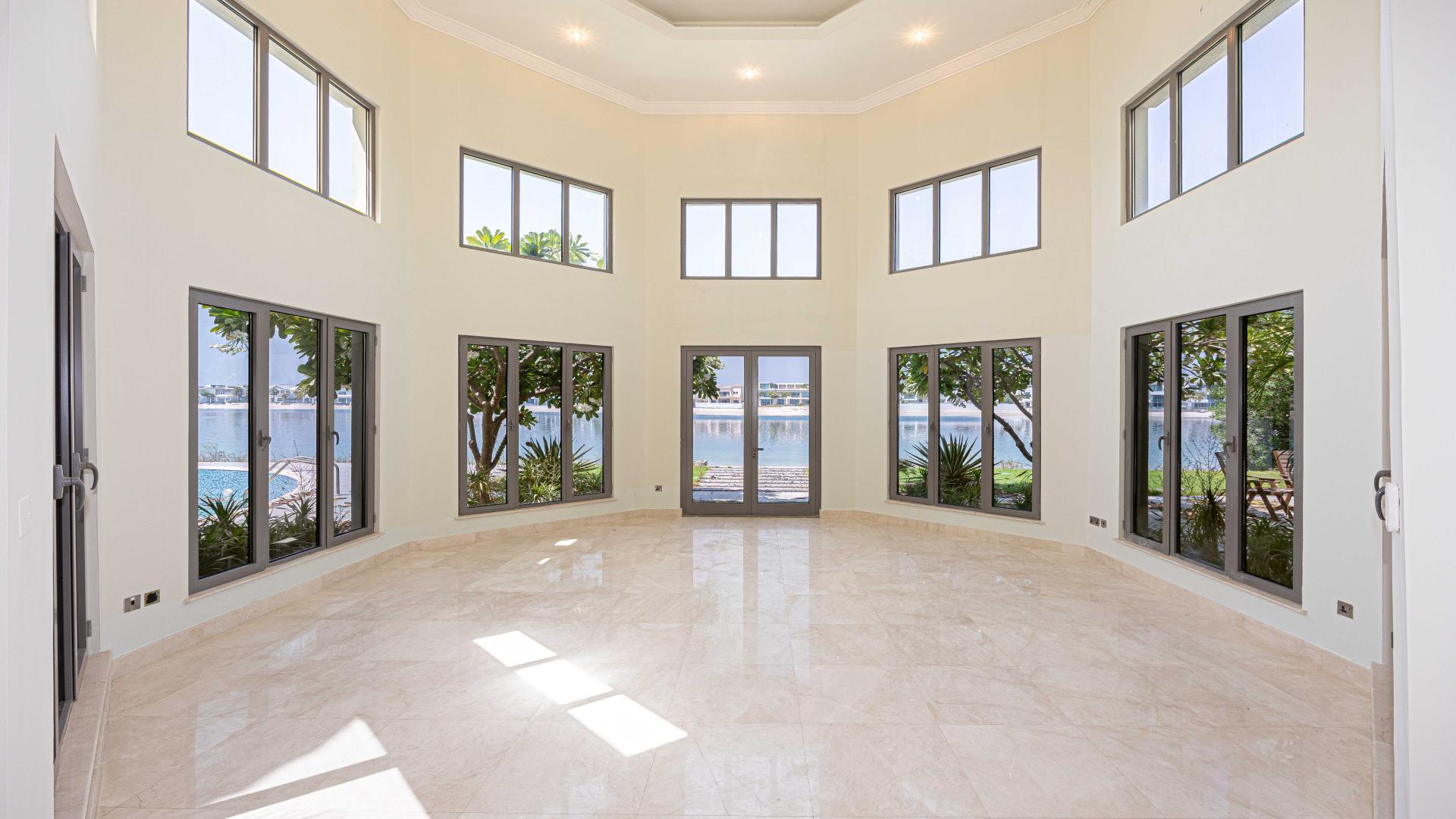 "Frond O Signature Villa exterior, Palm Jumeirah, beachfront location, 7 bedrooms, for rent.",Spacious living room with large windows overlooking waterfront at Palm Jumeirah Signature Villa