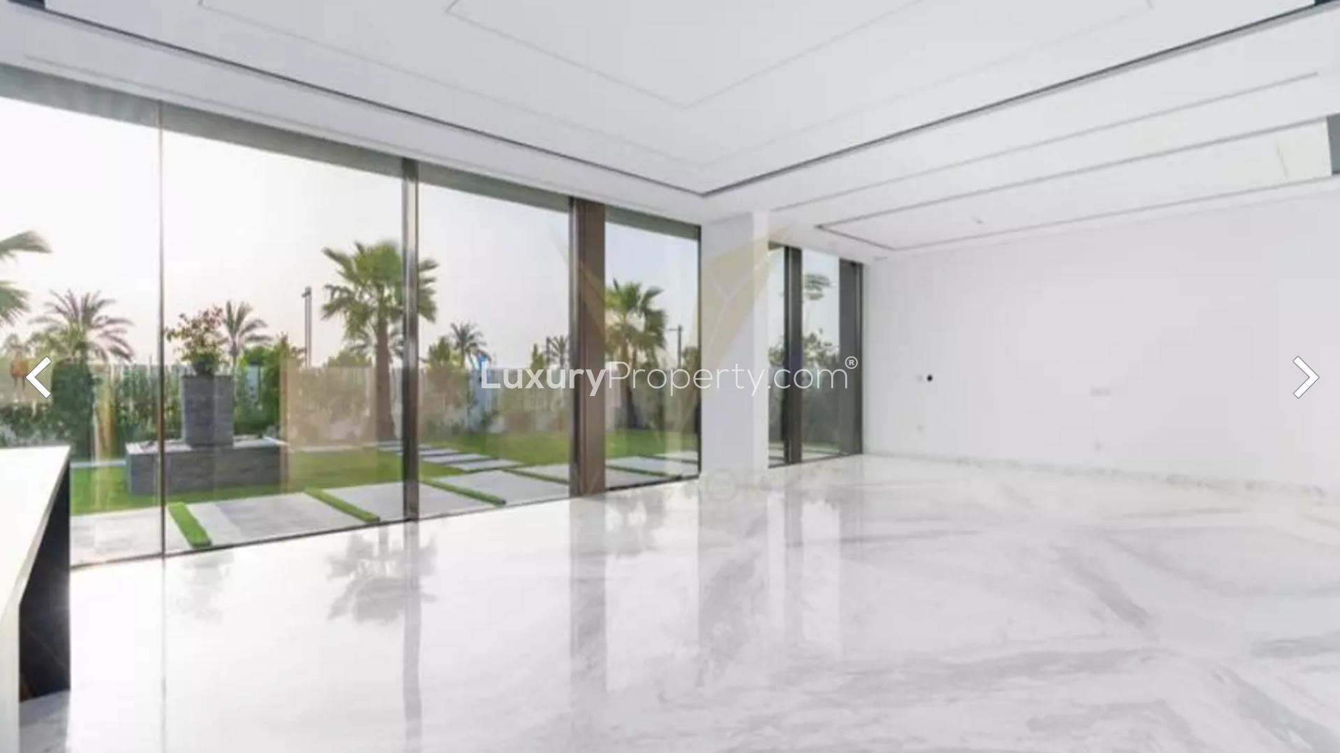 "Spacious interior with large glass doors overlooking lush garden in Dubai Hills luxury villa.",Luxury villa interior with marble floors and garden view in Dubai Hills Estate