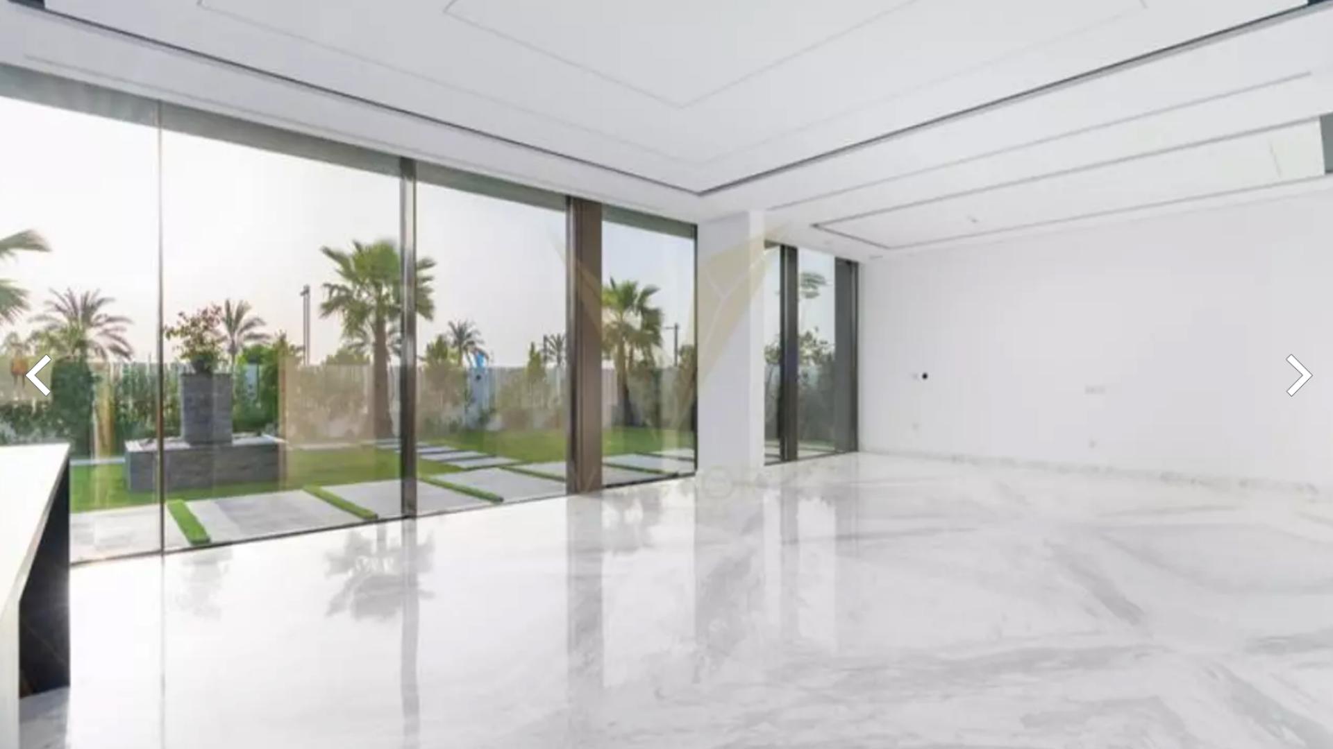 "Spacious interior with large glass doors overlooking lush garden in Dubai Hills luxury villa.",Luxury villa interior with marble floors and garden view in Dubai Hills Estate