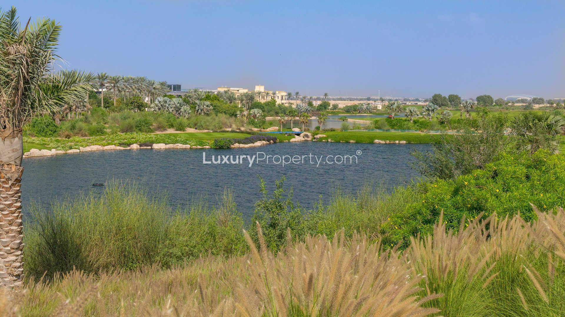 Modern eight-bedroom villa exterior in Dubai Hills Grove, spacious sandy yard, glass facade