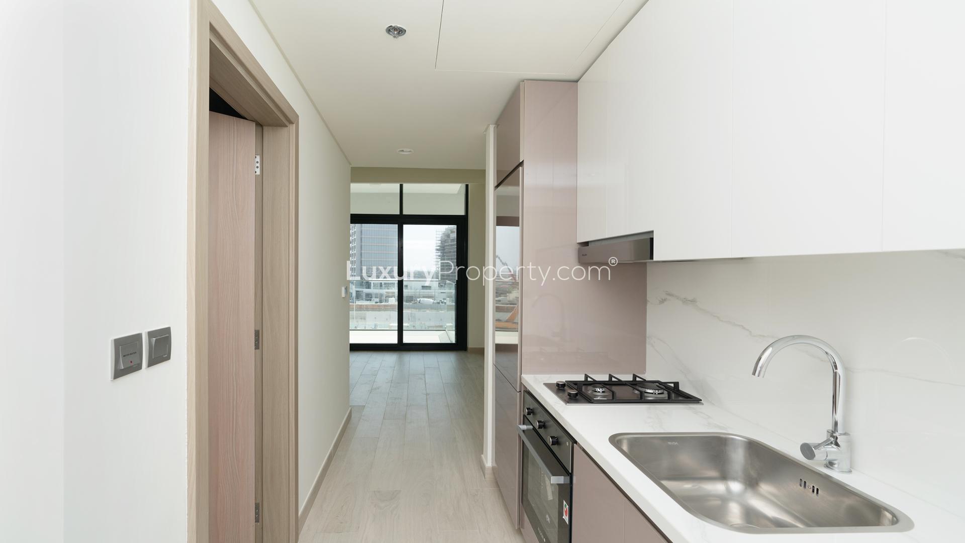 Alt text: "Balcony view from studio at Azizi Riviera, Meydan, overlooking construction site.",Modern kitchen in studio apartment at Azizi Riviera, Meydan One, featuring sleek design