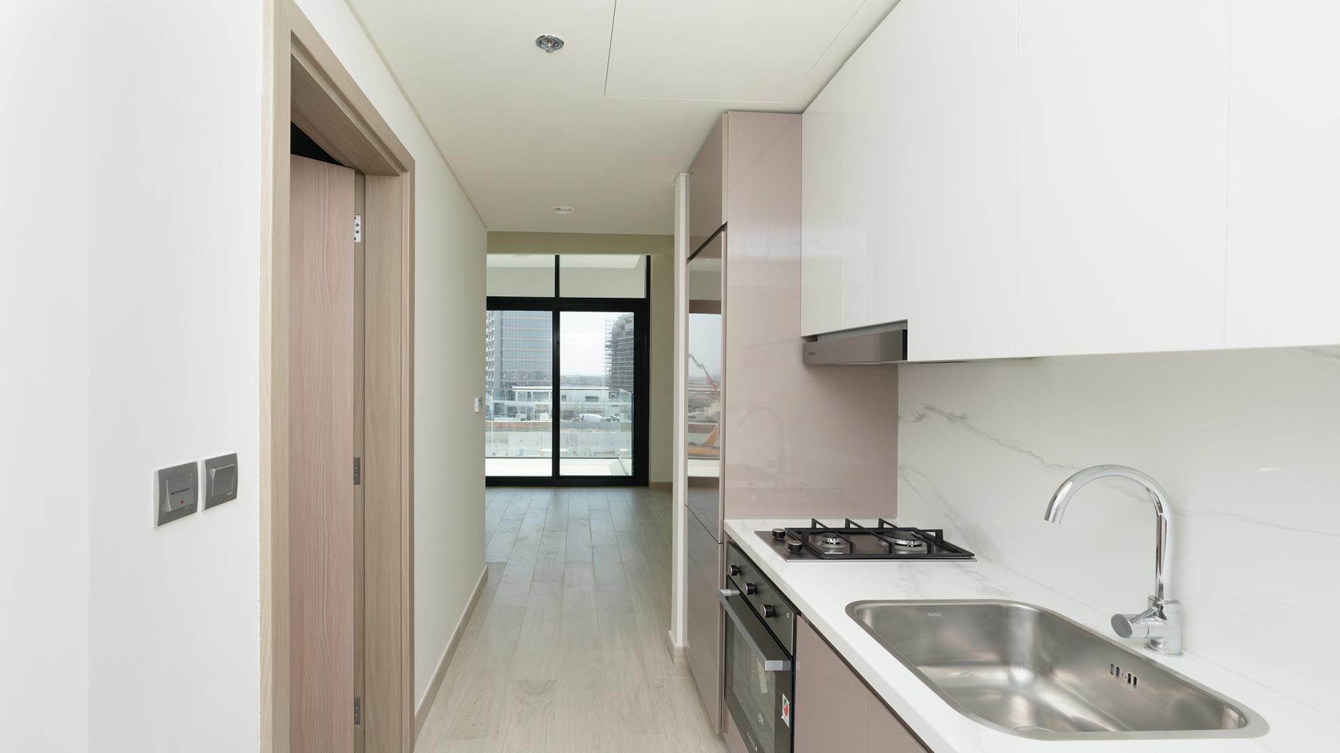 Alt text: "Balcony view from studio at Azizi Riviera, Meydan, overlooking construction site.",Modern kitchen in studio apartment at Azizi Riviera, Meydan One, featuring sleek design