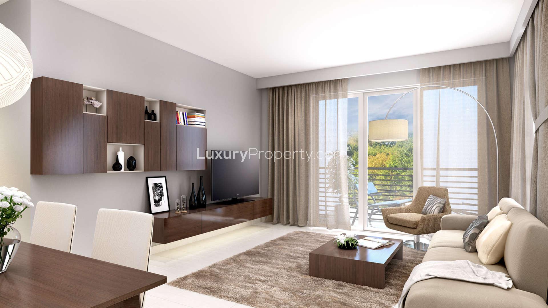 "Modern Zahra Apartments exterior with pool, Town Square Dubai, 2-bedroom for sale.",Modern living room in 2-bedroom Zahra apartment, Dubai Town Square, featuring stylish decor and balcony