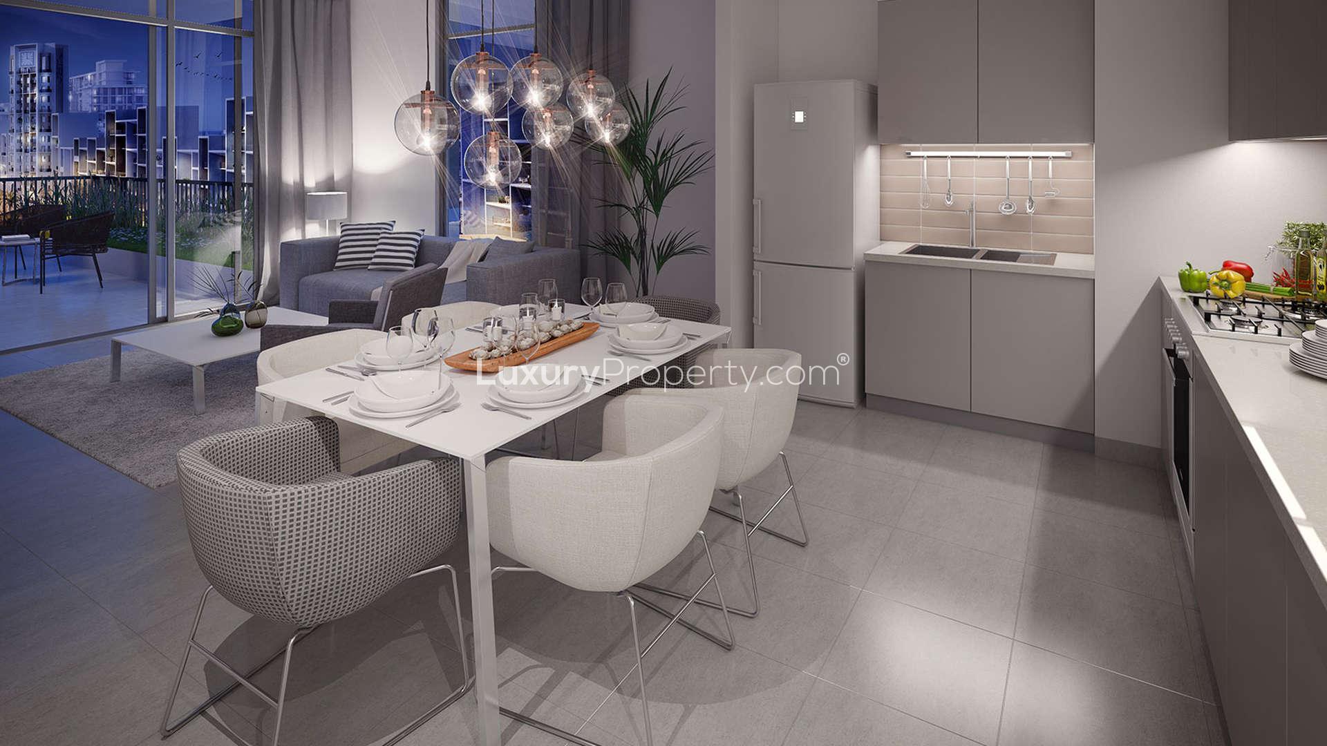 "Modern Warda Apartments exterior view with palm-lined street, Town Square Dubai.",Modern kitchen and dining area in Warda Apartments, Dubai Town Square, stylishly furnished
