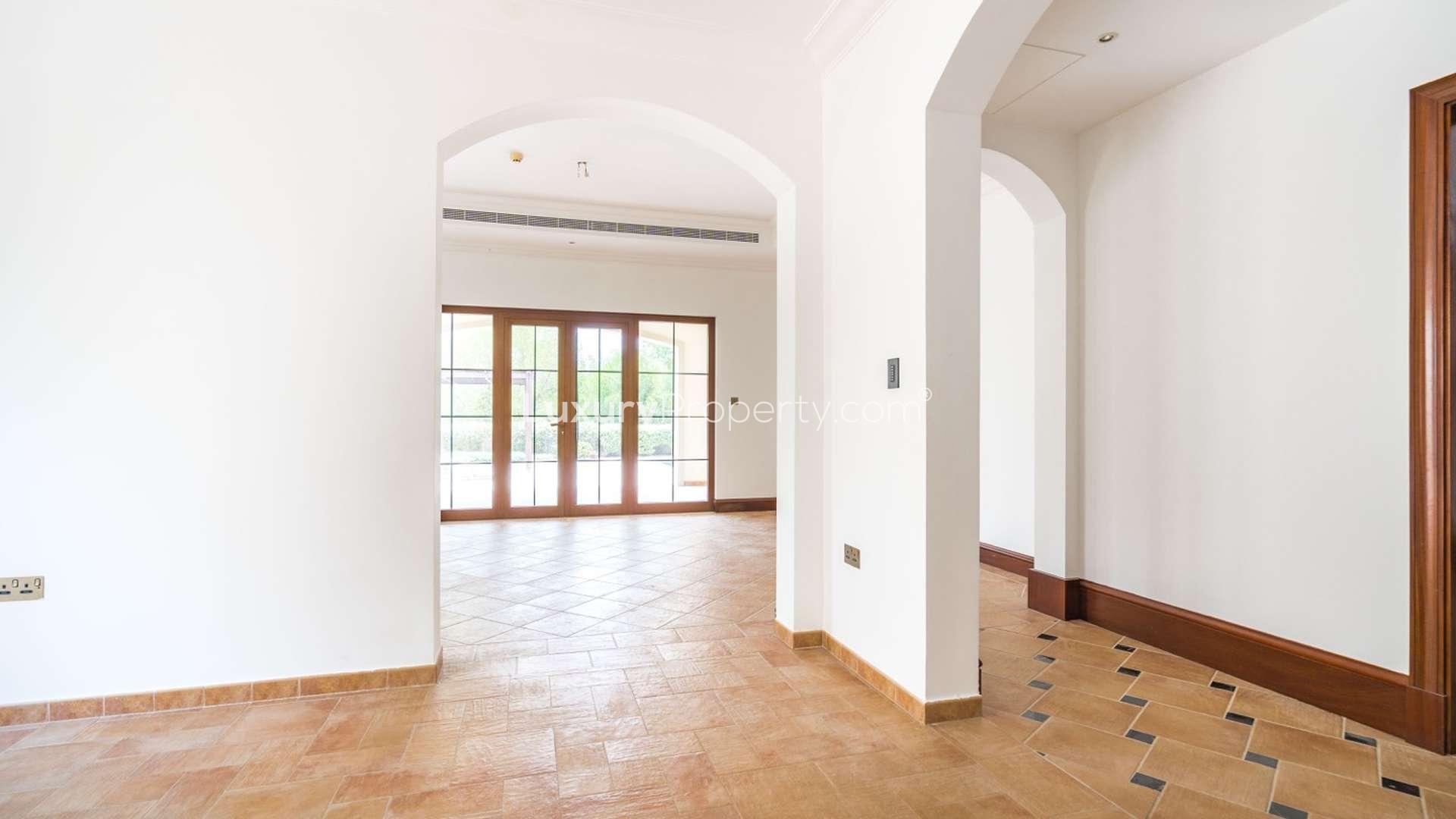 Elegant hallway in Jumeirah Golf Estates villa with arched doorways and tiled floor