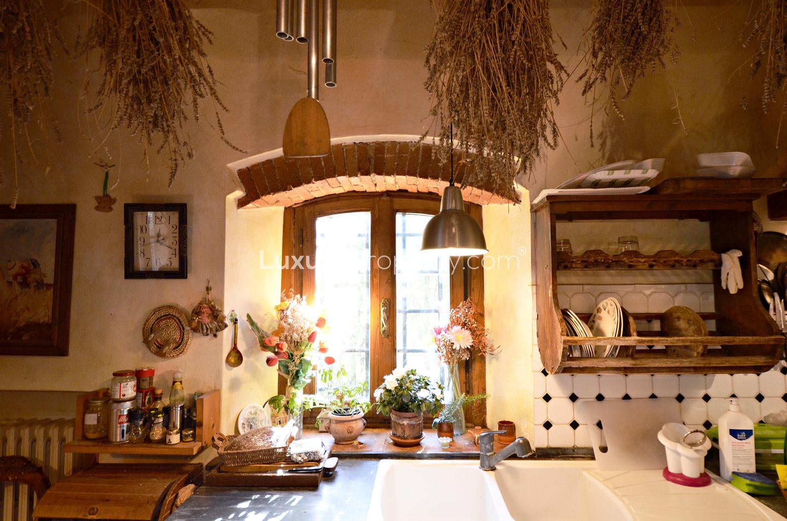"Charming patio view at 7-bedroom villa in Florence Tuscany countryside, Casa Nella Collina.",Rustic kitchen with herbs, wooden shelves, and vintage decor in Tuscany villa, Florence countryside