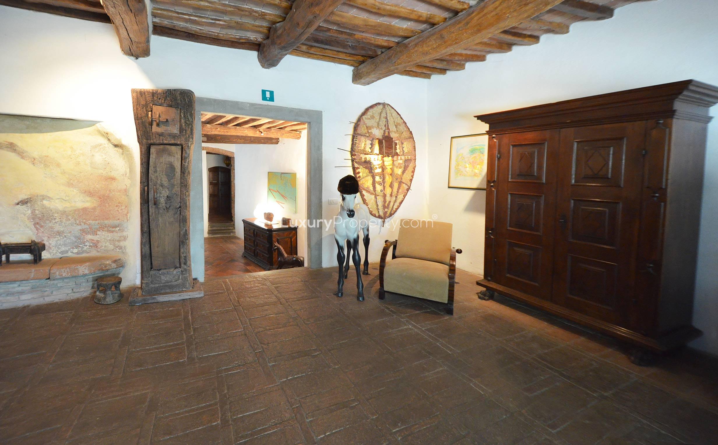 Rustic Tuscan villa interior with stone walls, wooden beams, and cozy red seating area