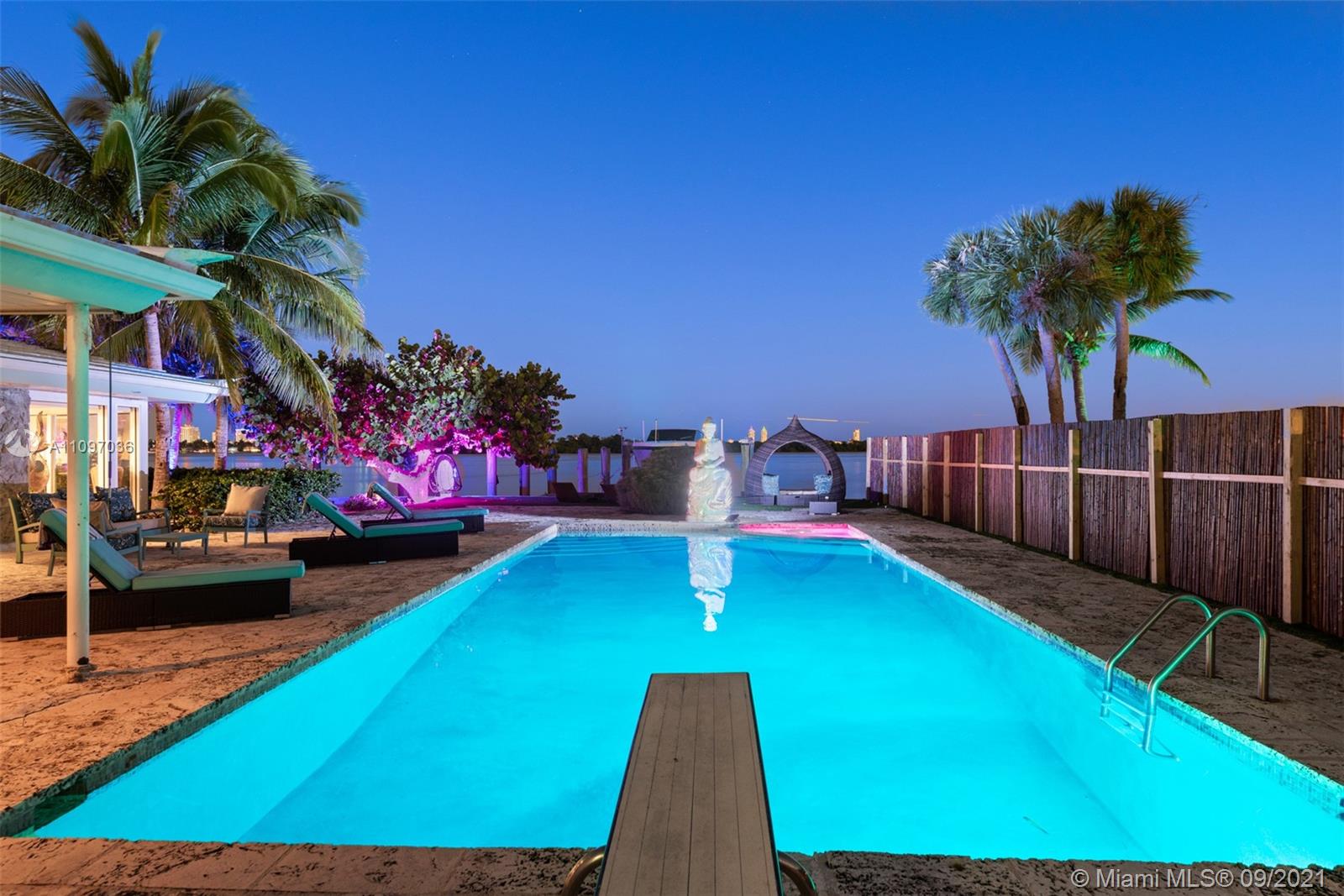 "Waterfront view from luxury Belle Meade Island residence in Miami, featuring palm trees and lounge.",Luxurious Miami Belle Meade Island home with pool, palm trees, and night sky view