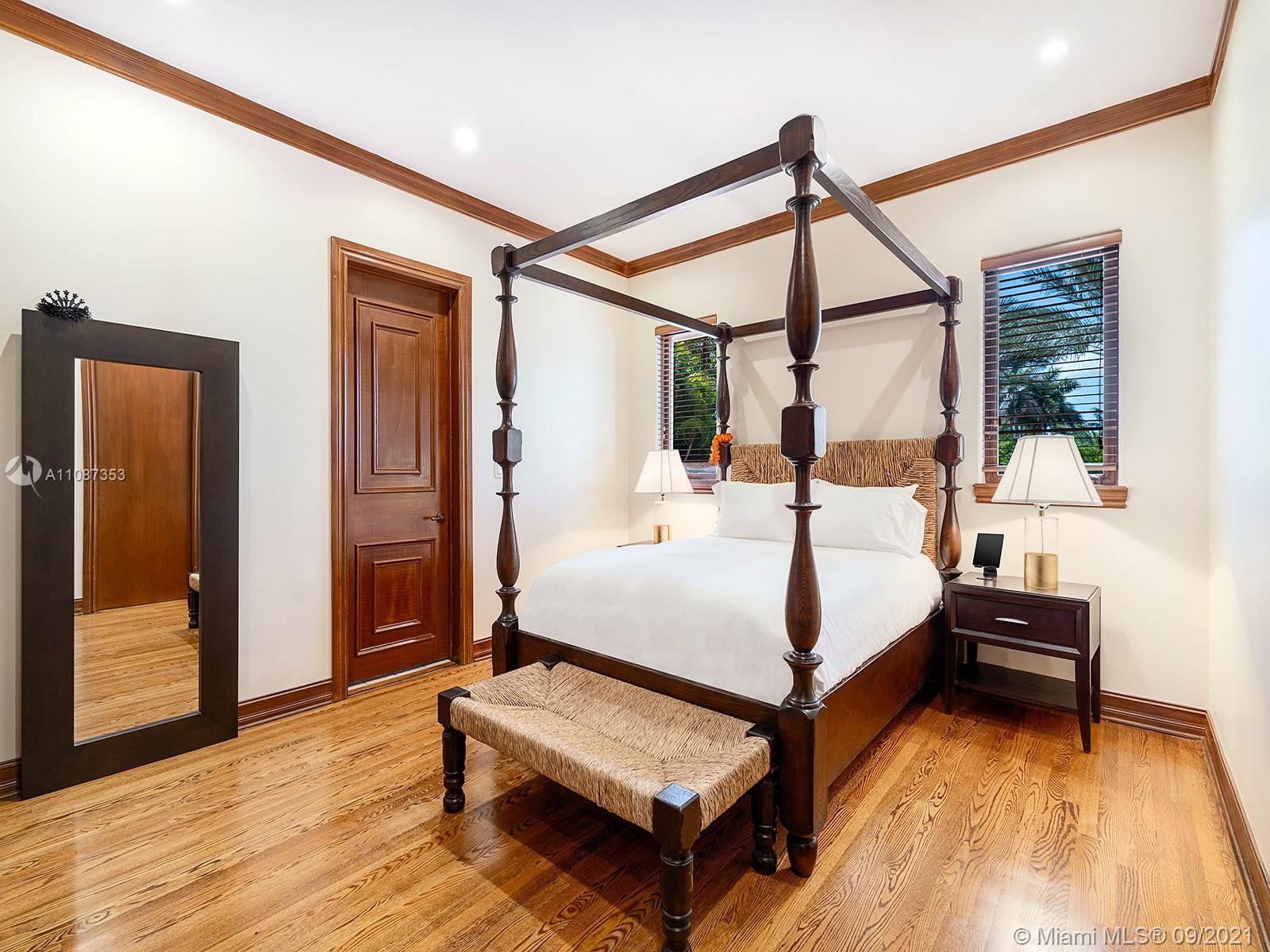 "Home gym with modern equipment and bay views in Miami villa for sale, Florida.",Luxurious bedroom in 9-bedroom bayfront villa, Miami, featuring elegant wooden decor and furnishings