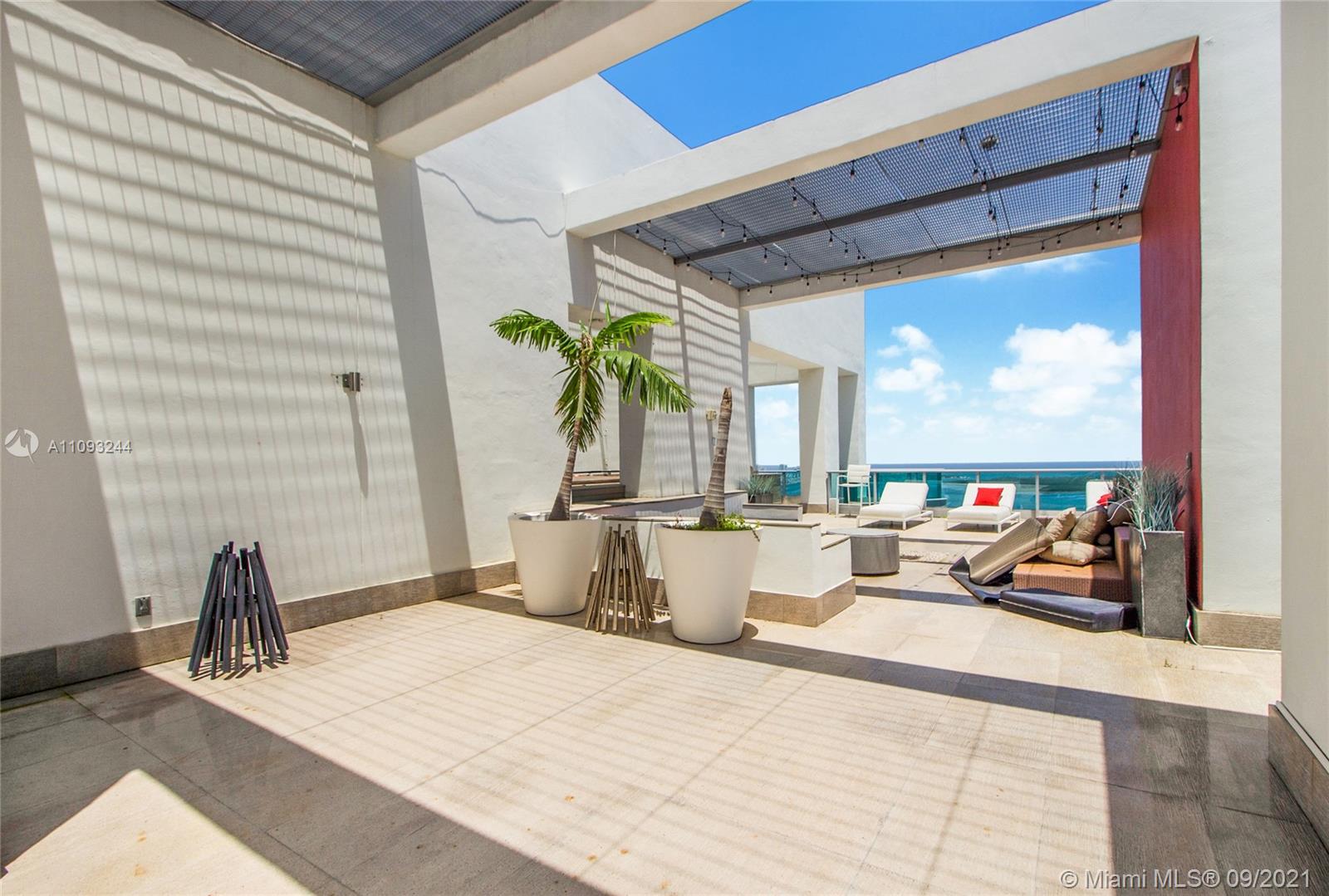 Outdoor terrace with ocean view at Miami Beach penthouse, featuring grill and lounge chairs
