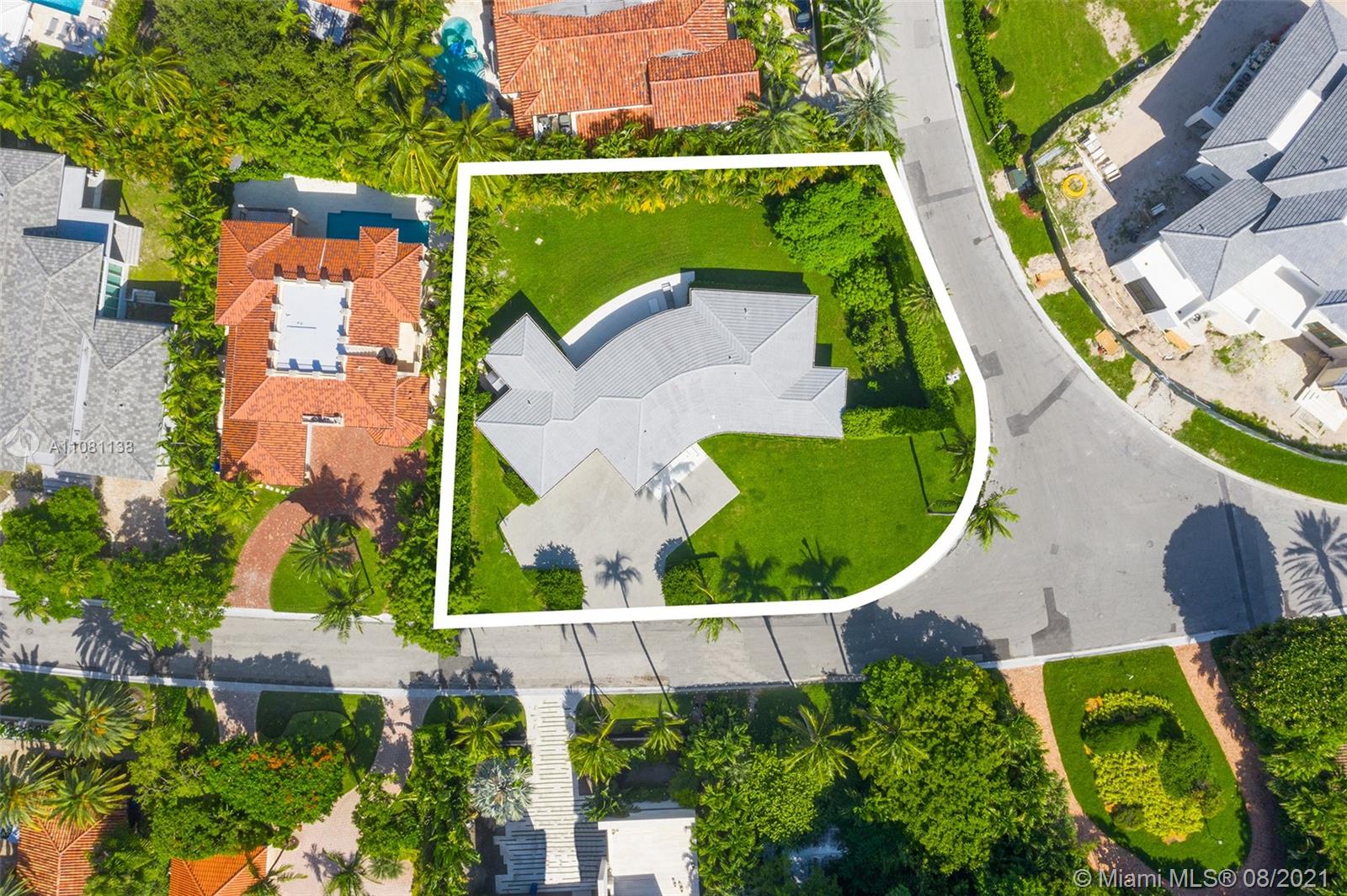 Aerial view of Bal Harbour villa, waterfront location, lush greenery, Miami skyline in background