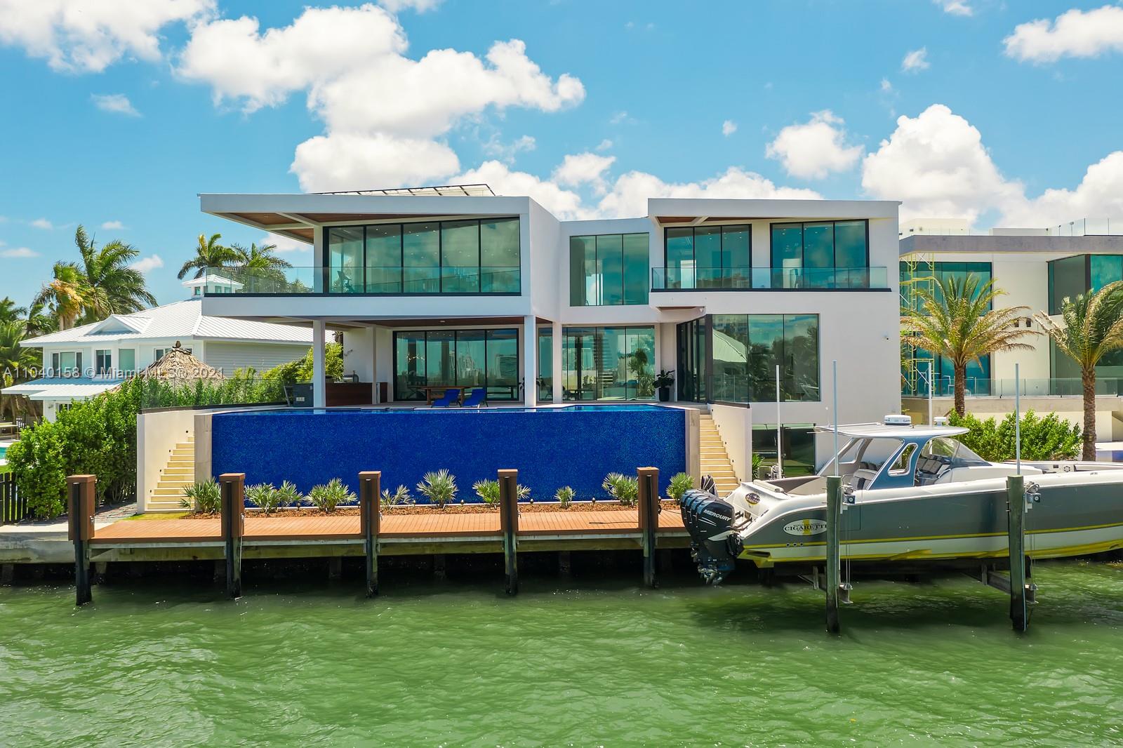 "Elegant 3-story villa exterior with lush landscaping, Belle Meade Island, Miami.",Luxurious 3-story villa with waterfront view and boat dock on Belle Meade Island, Miami