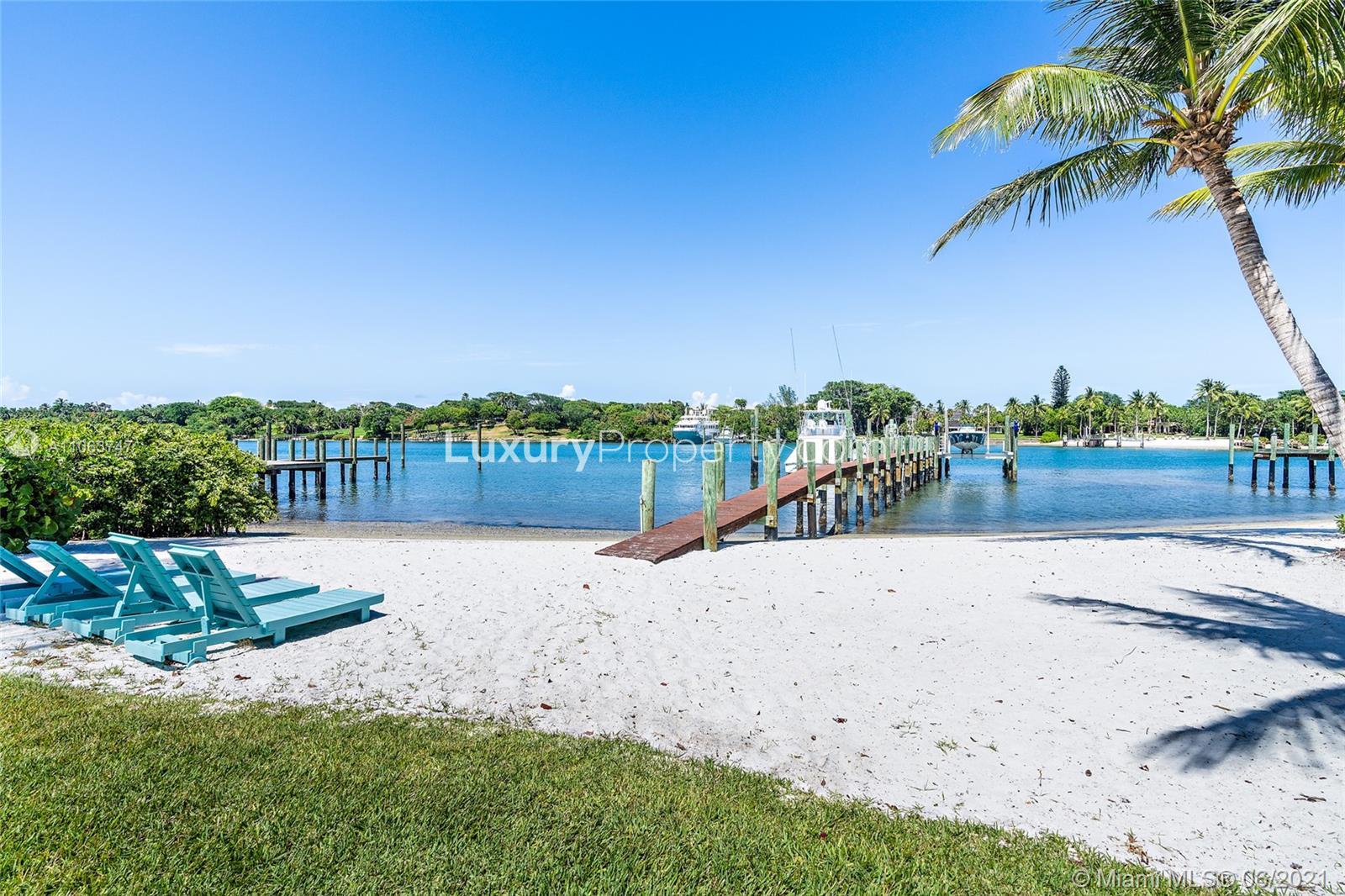 Luxury 6-bedroom villa with waterfront view, palm trees, and private dock in Tequesta, Florida