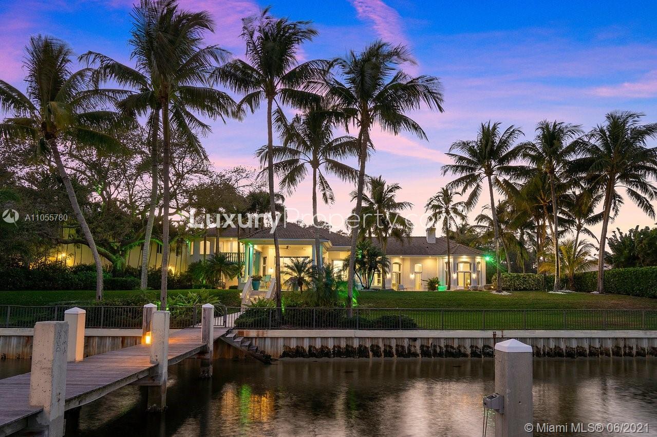 Waterfront luxury villa with palm trees at sunset, Miami estate for sale