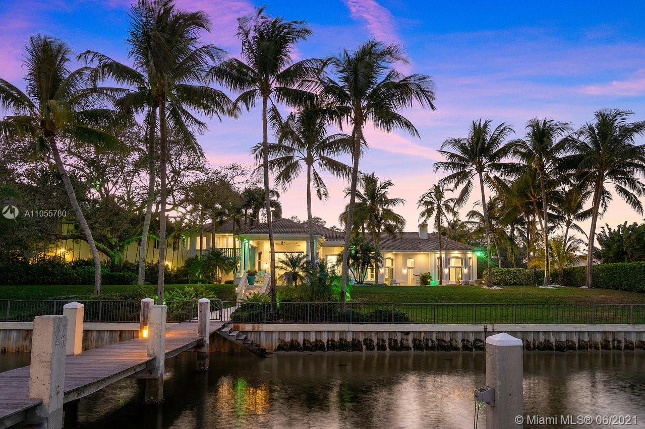 Waterfront luxury villa with palm trees at sunset, Miami estate for sale