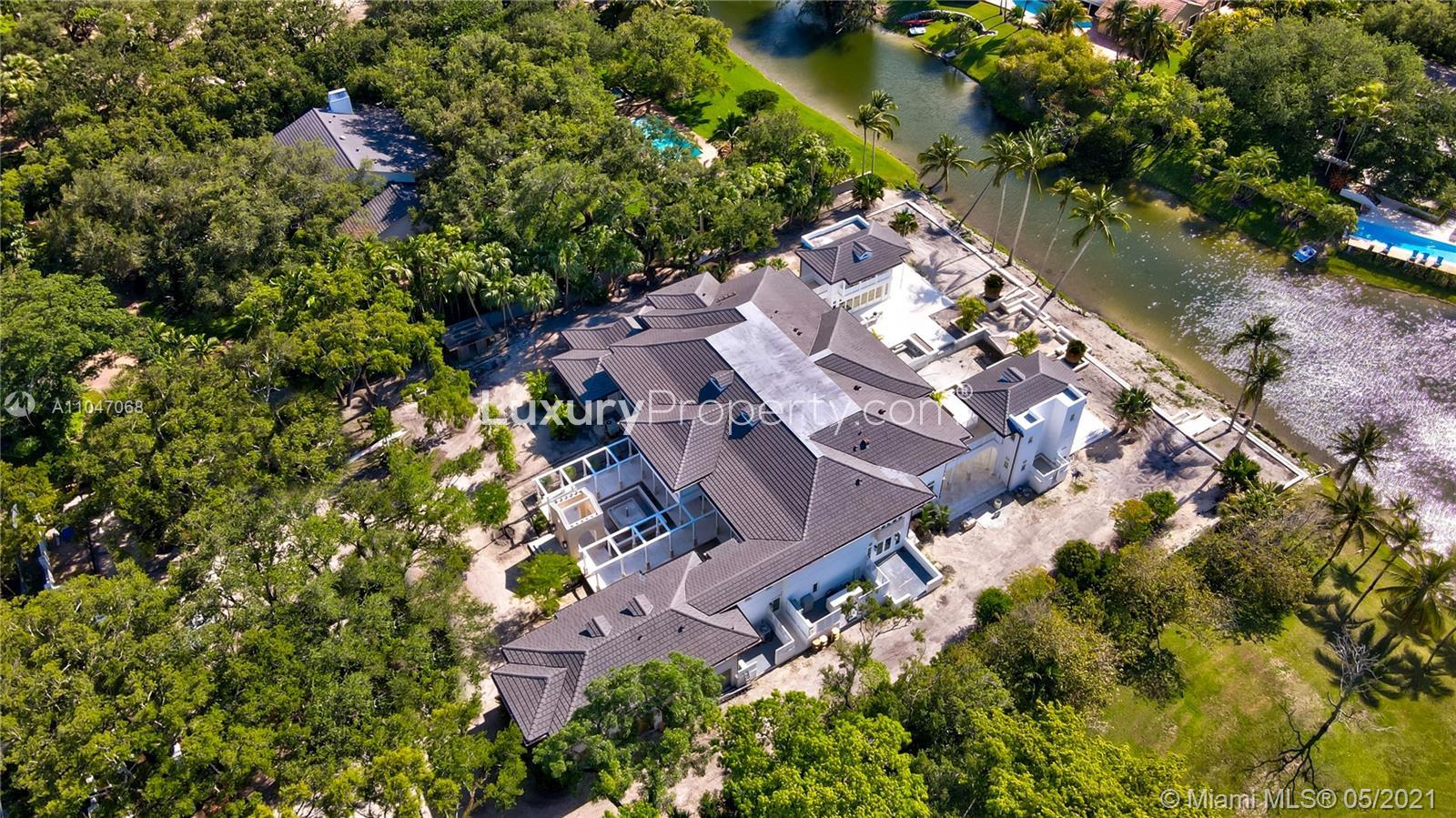 Lakefront estate view with palm trees at 10900 Lakeside Dr, Coral Gables, Miami villa