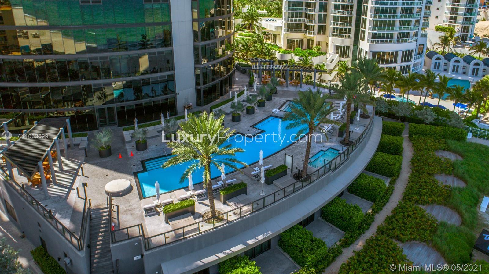 Luxury Miami villa pool with ocean view, palm trees, and sunlit sky at Collins Ave
