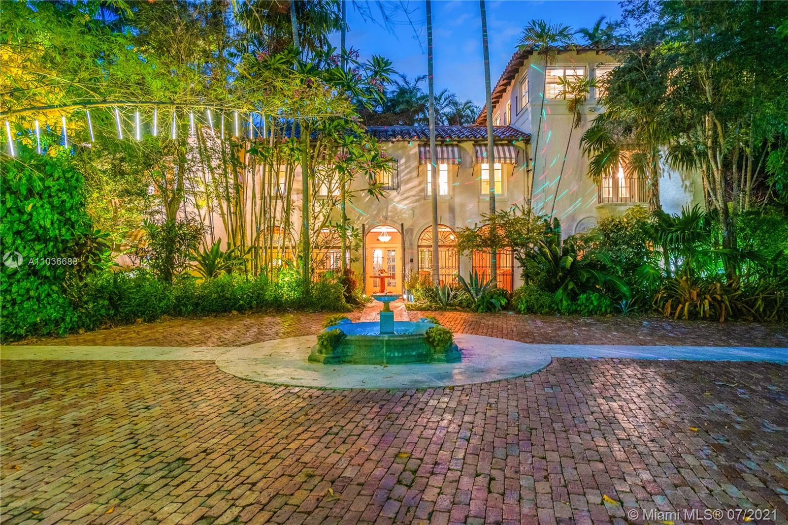 Aerial view of Miami villa courtyard with umbrellas and greenery, 6-bed estate for sale