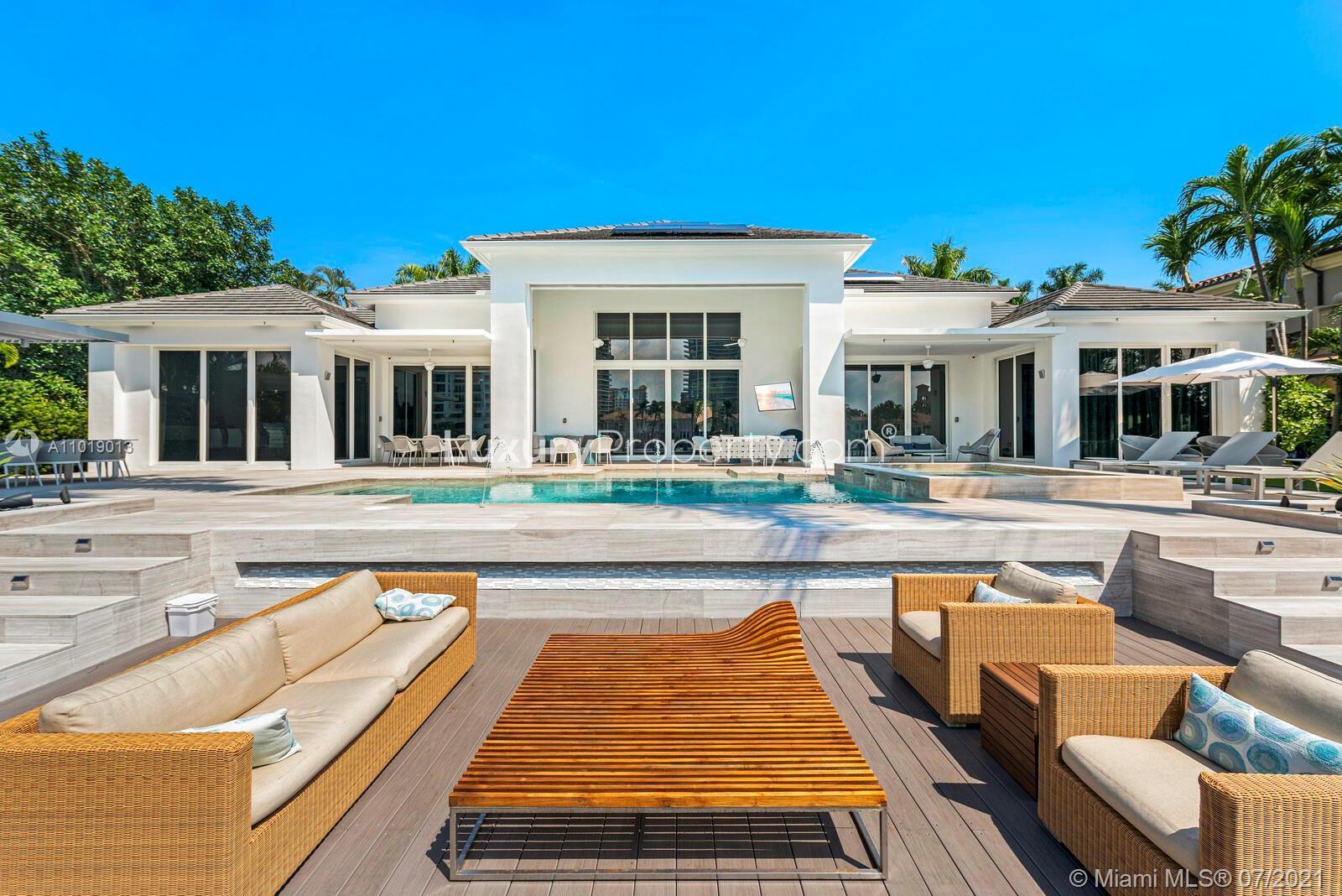 Modern villa exterior with palm trees and luxury car in Golden Beach, Florida