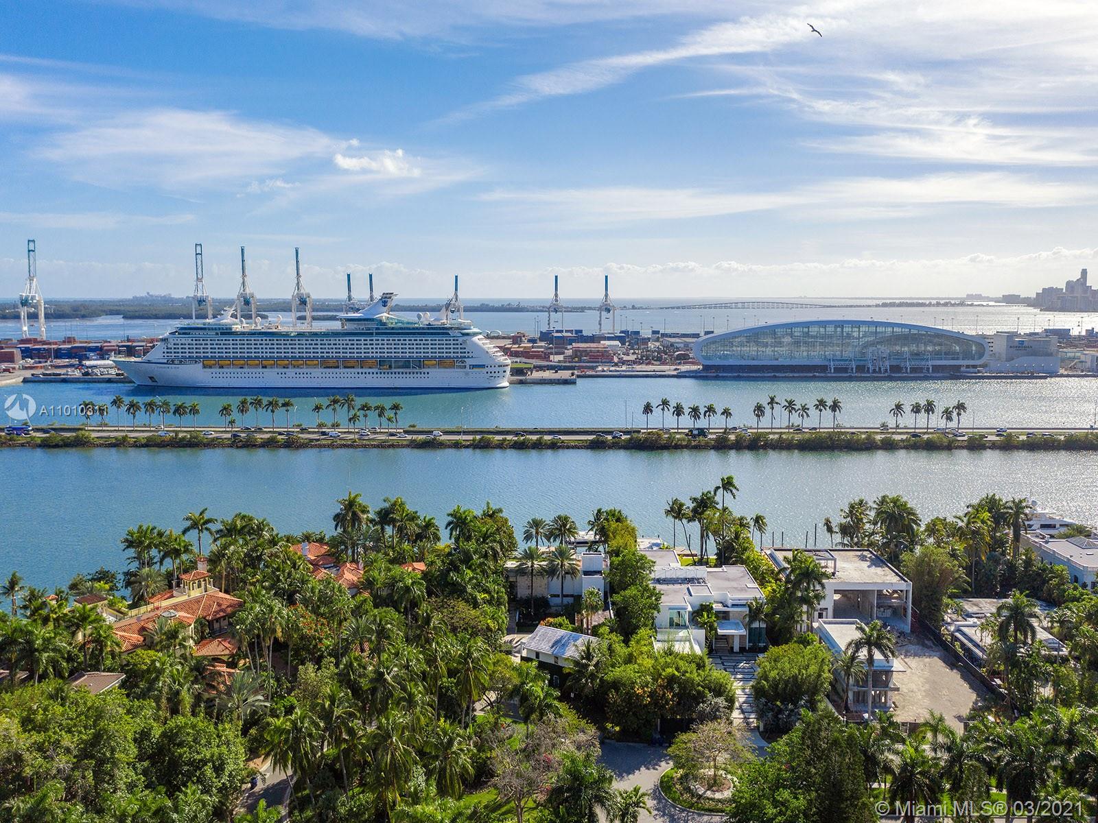 Luxury Miami villa with waterfront view, boat dock, lush greenery, and modern architecture