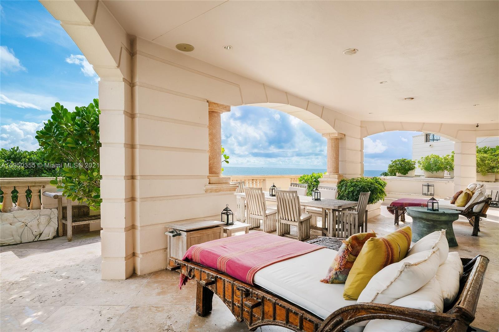 Ocean view villa patio with dining area, lounge chairs, and lush greenery in Miami