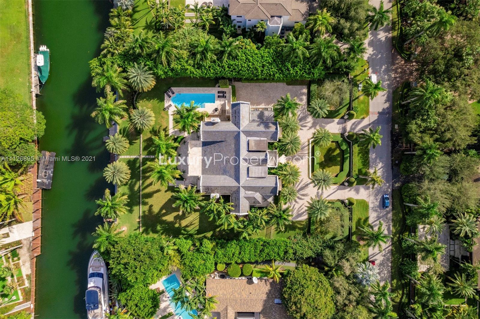 Luxurious Miami waterfront villa exterior with palm trees and manicured garden at 585 Arvida Pkwy