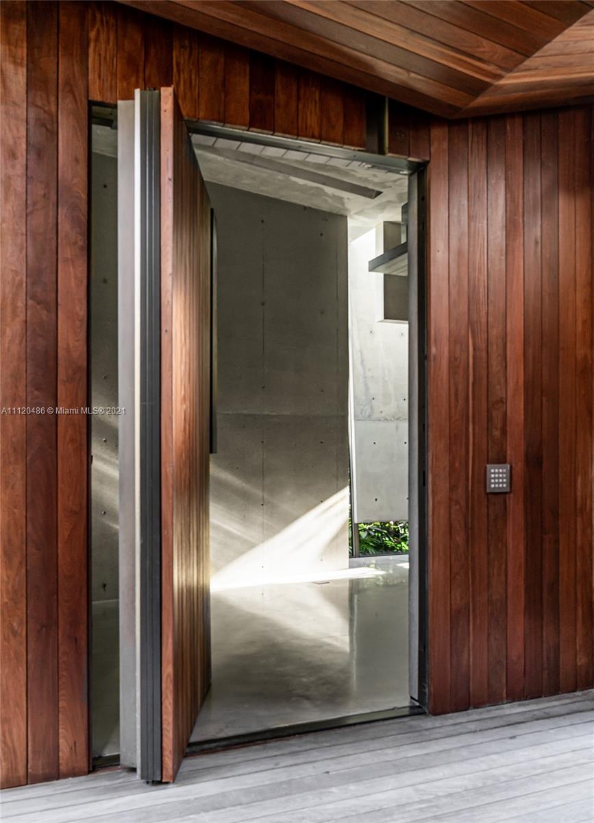 "Modern Miami villa exterior with lush greenery at 2038 Prairie Ave, Florida, for sale.",Open wooden door entrance of luxury villa at 2038 Prairie Ave, Miami