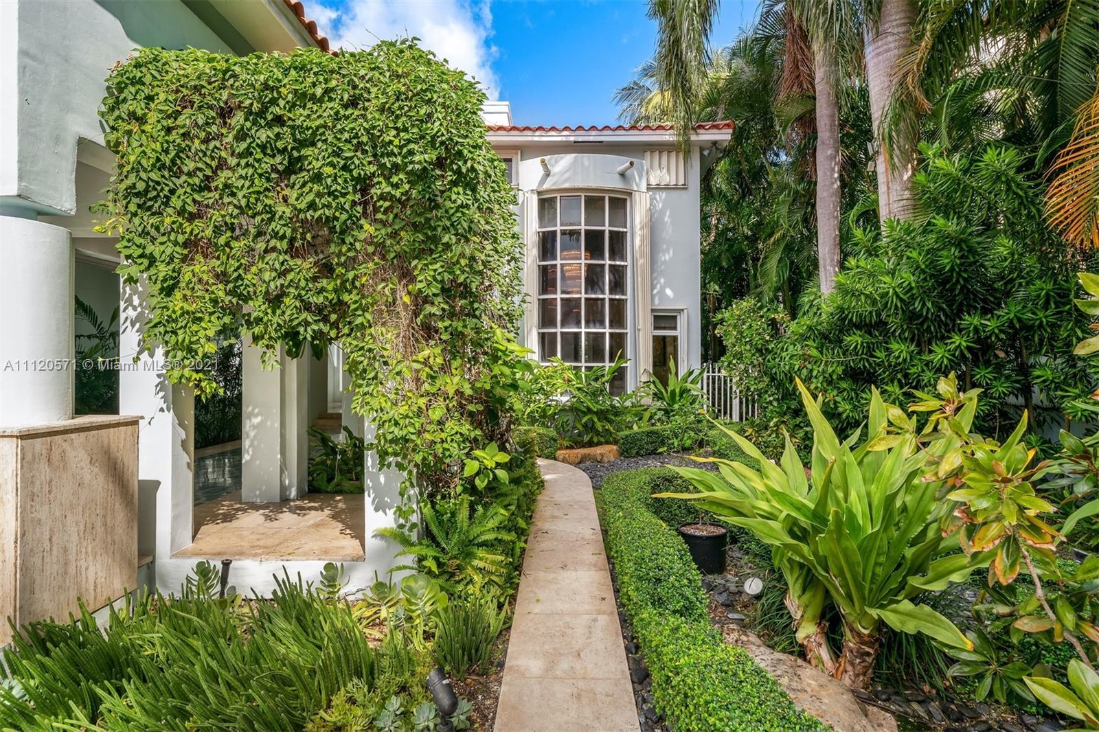 "Front view of 5-bedroom villa at 1335 N Venetian Way, Miami, with lush greenery.",Lush garden entrance of 5-bedroom villa at 1335 N Venetian Way, Miami, Florida
