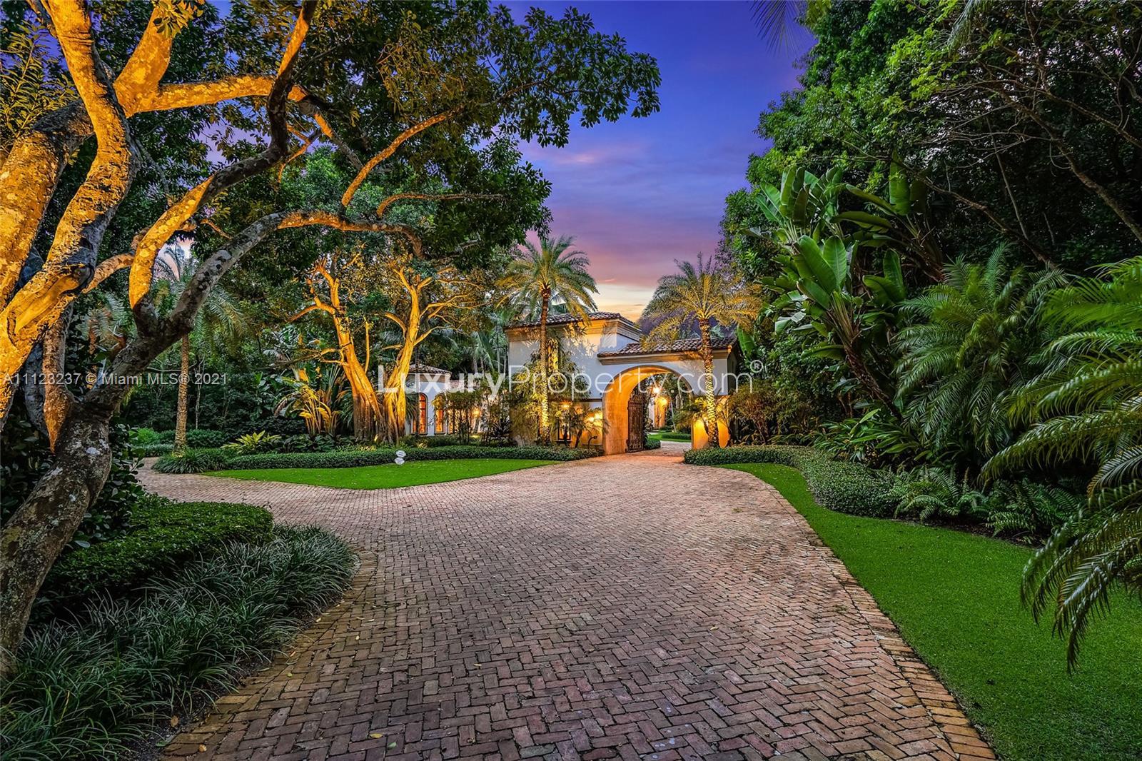 Luxurious waterfront villa at sunset with lush landscaping and palm trees, Hobe Sound, Florida
