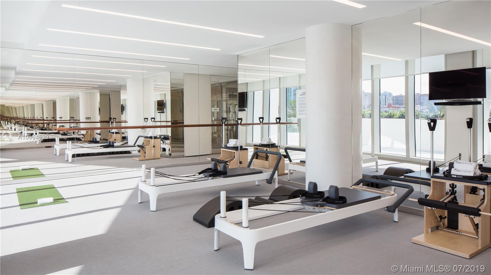 "Modern gym with exercise bikes in Miami penthouse for sale, 16901 Collins Avenue.",Modern fitness room in luxury Miami penthouse villa, featuring Pilates equipment and mirrored walls