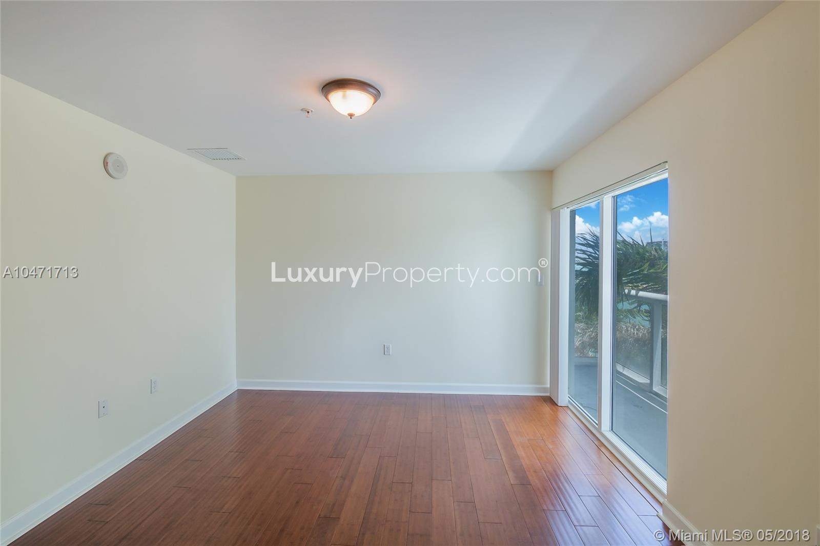 Empty room with hardwood floors and large window in Miami waterfront condo