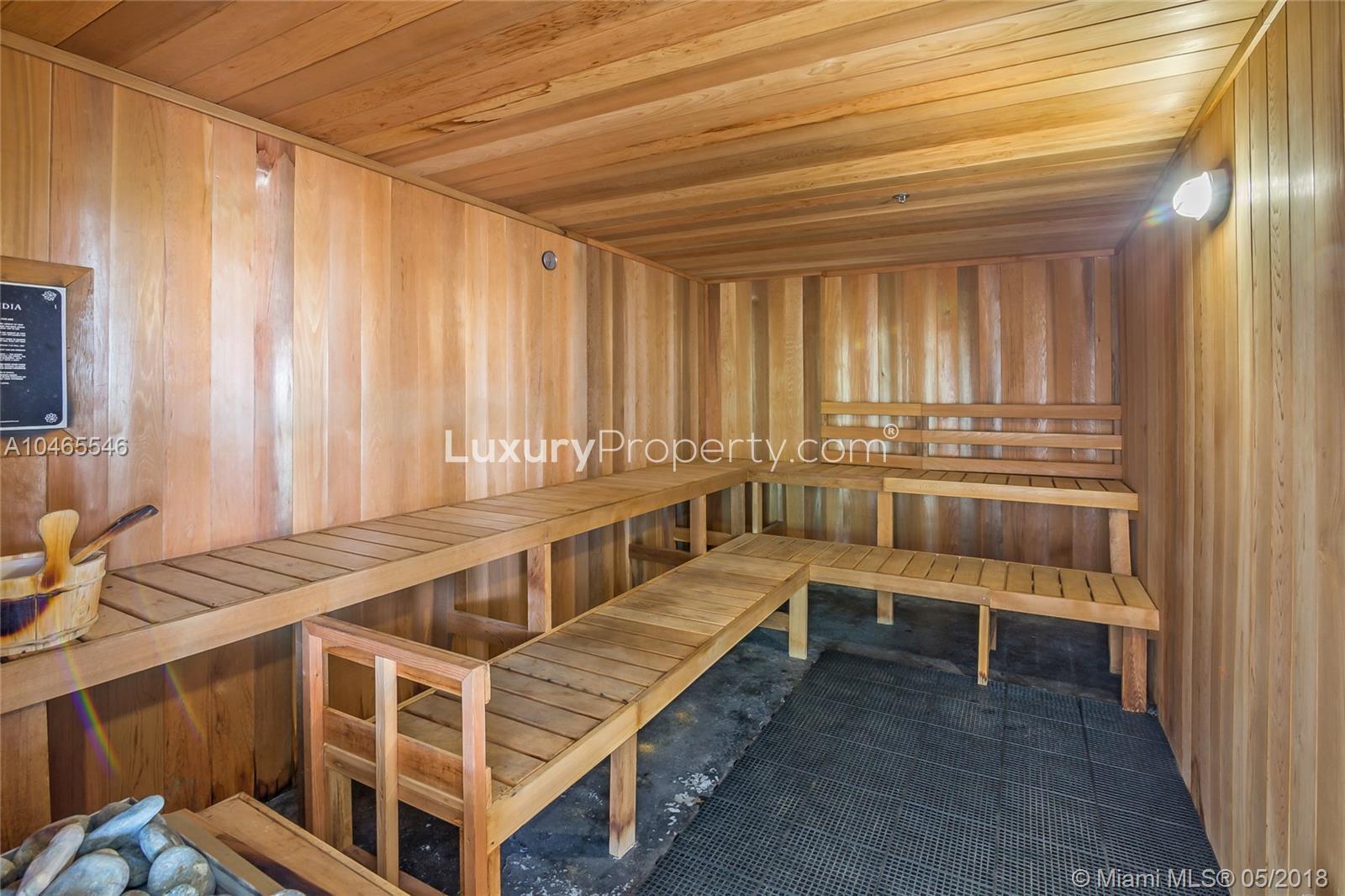 "Modern gym in waterfront condo, North Bay Village, Miami, with ocean view and equipment.","Luxurious sauna in modern waterfront condo, North Bay Village, Miami villa for sale.",Modern condo lobby in North Bay Village, Miami with large windows and elegant seating area