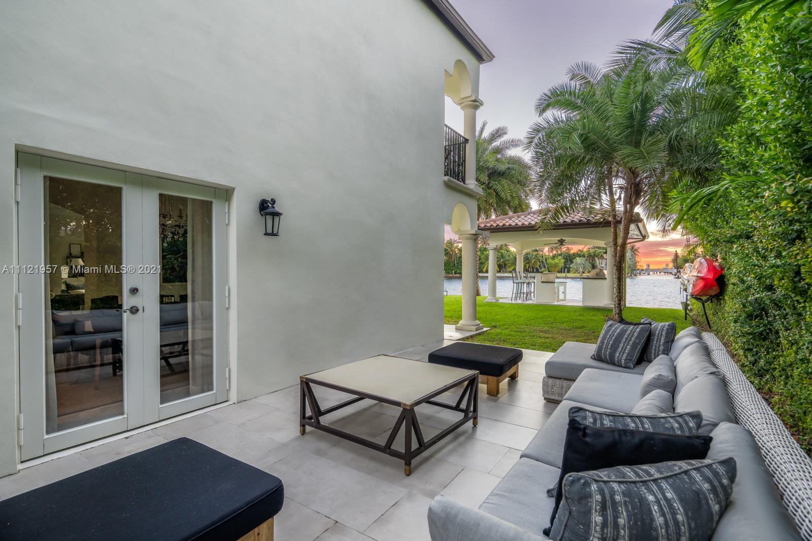 "Luxury waterfront Mediterranean villa with patio and garden at dusk, Miami, Florida.",Outdoor patio of waterfront Mediterranean villa in Miami, with lush garden and canal views