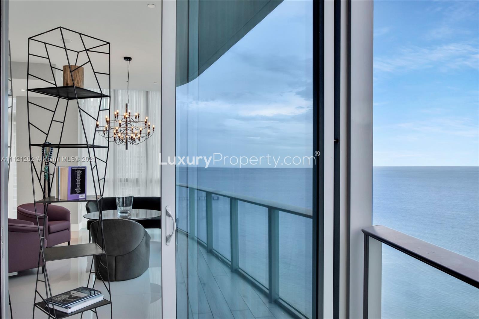 "Modern elevator lobby in luxury Miami villa at 17475 Collins Ave, Florida, for sale.",Luxurious Miami villa interior with ocean view, modern decor, and elegant chandelier