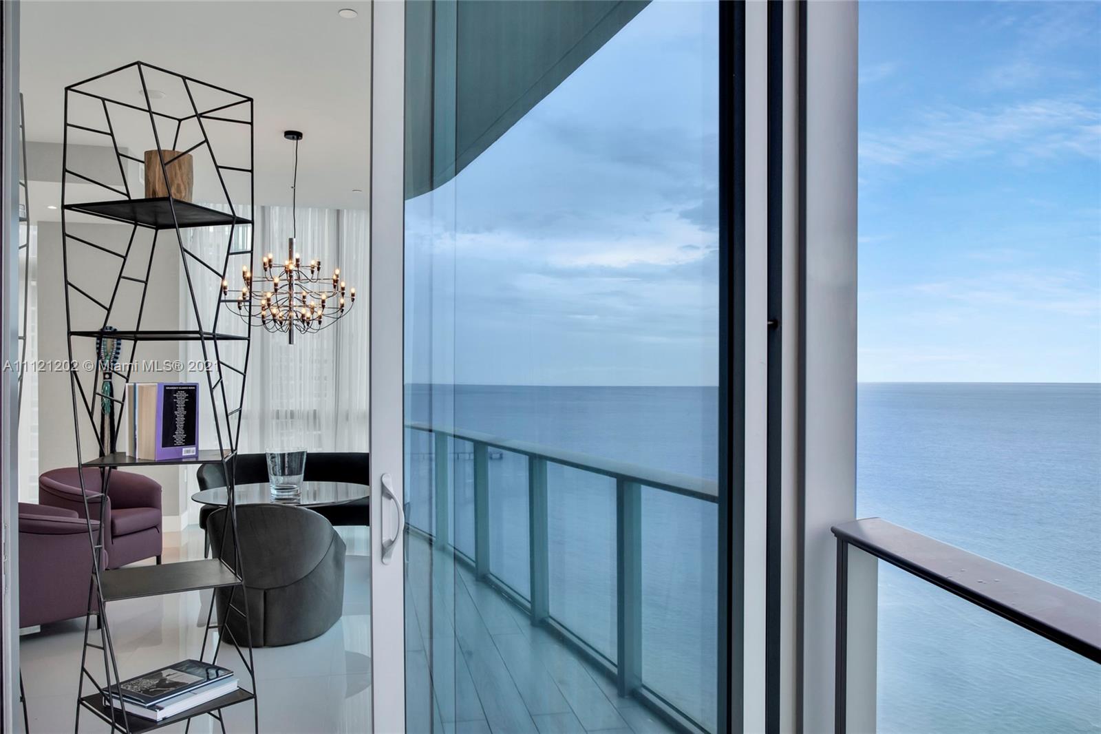 "Modern elevator lobby in luxury Miami villa at 17475 Collins Ave, Florida, for sale.",Luxurious Miami villa interior with ocean view, modern decor, and elegant chandelier