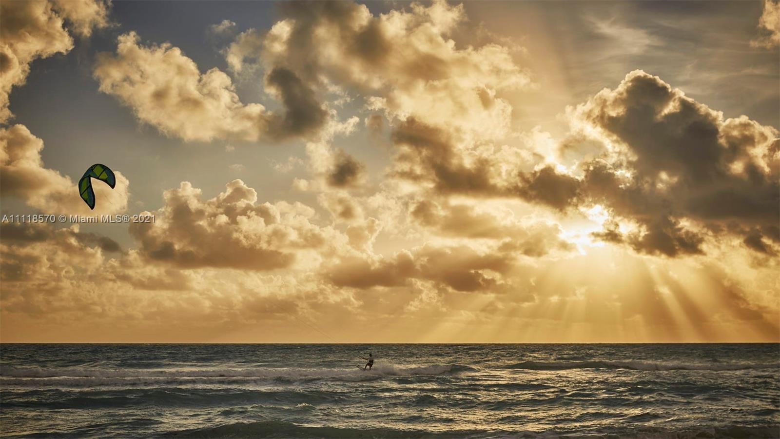 Oceanfront view from Miami villa, sandy beach with loungers and umbrellas under clear sky