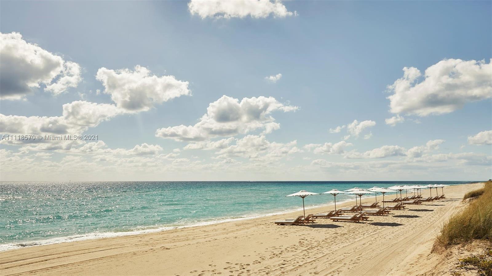 Oceanfront villa balcony with dining area, overlooking pool and palm trees at Collins Ave, Miami