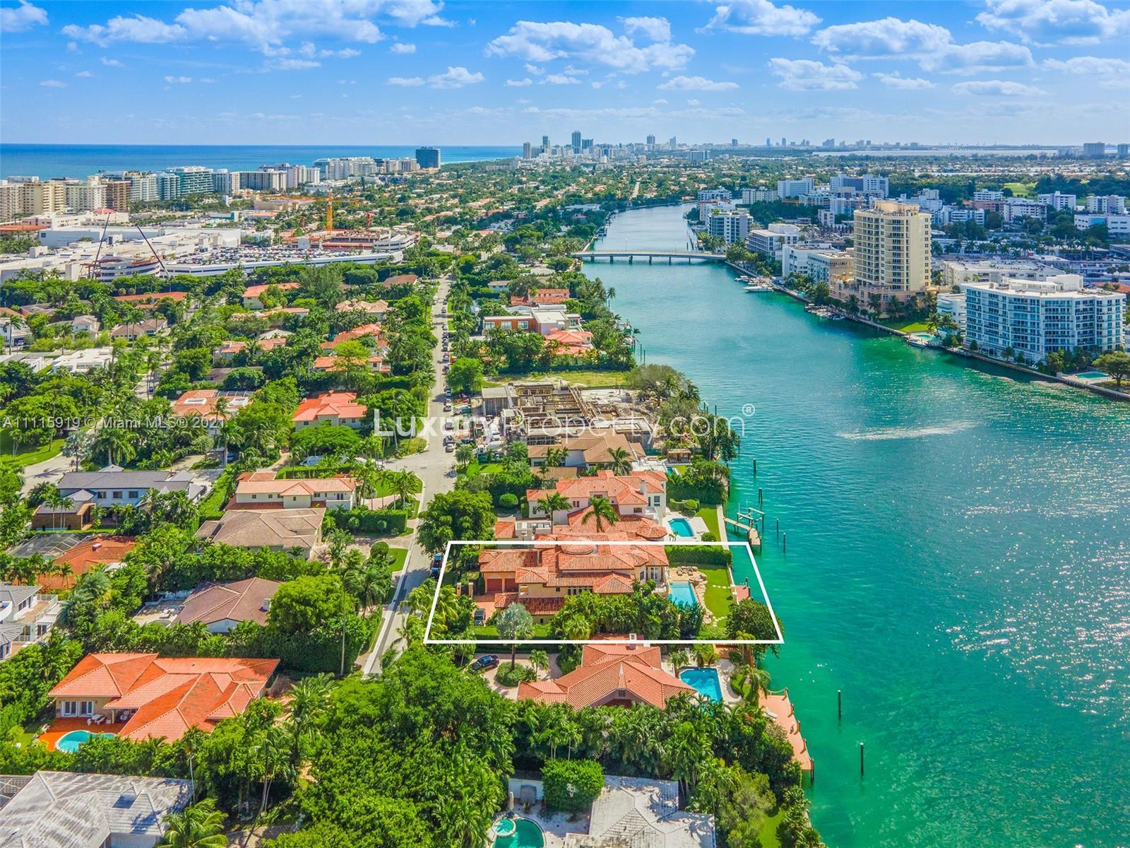 Aerial view of waterfront villa for sale in Miami, Florida, with ocean and cityscape backdrop