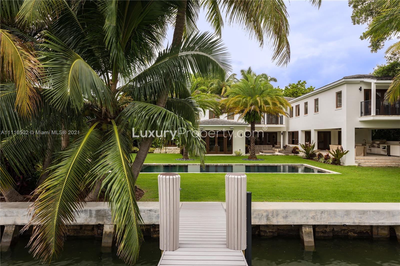 Renovated Miami waterfront villa with pool, palm trees, and modern architecture for sale