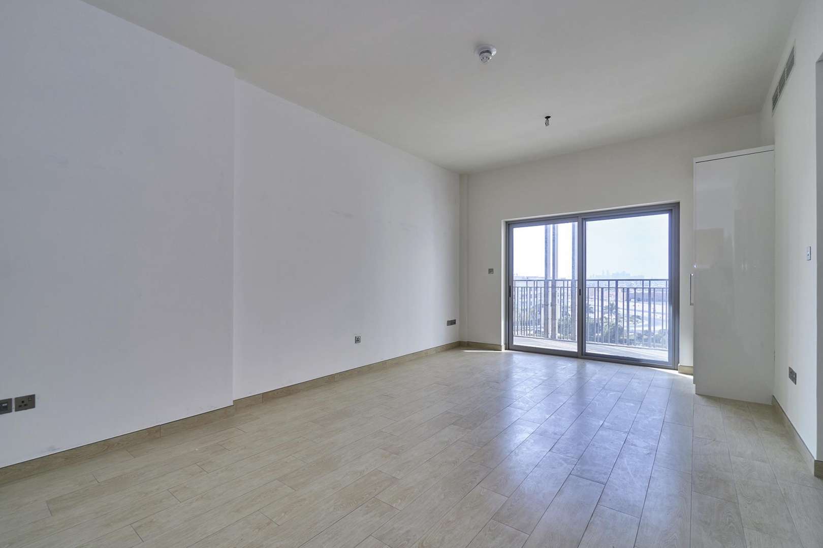 Studio apartment interior with open wardrobe, wooden door, and tile flooring in Genesis, Arjan